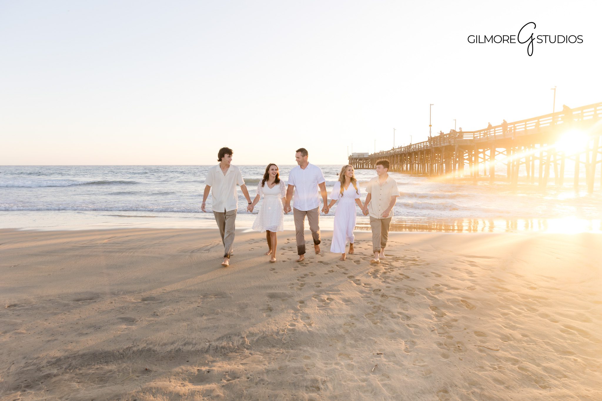 Oceanfront family photographer capturing sunset silhouettes by the pier.
Candid portrait photography with kids running on Newport Beach at sunset.