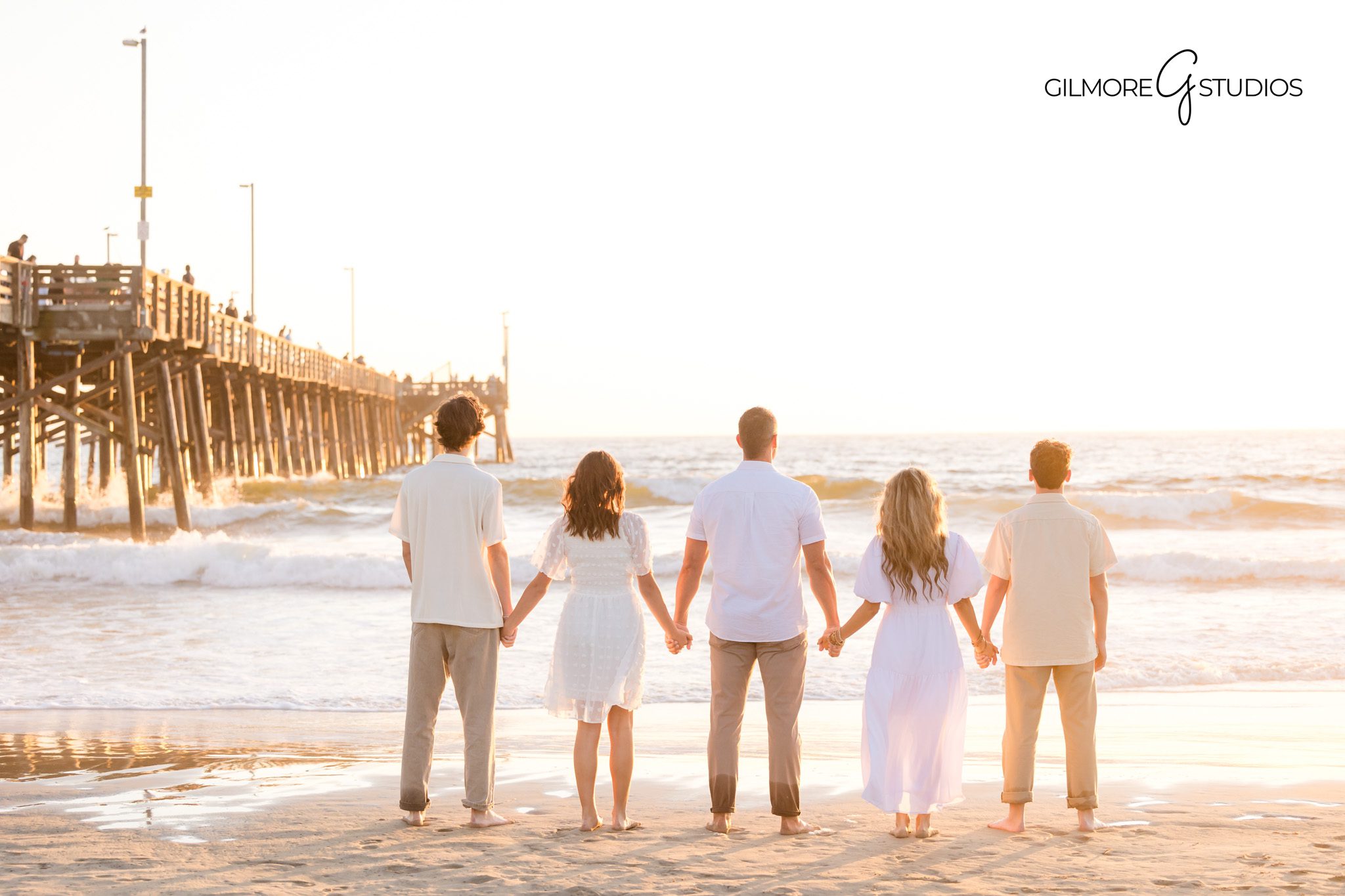 Golden hour portrait photography of family on the sand by the pier.
Newport Beach Pier sunset photographer capturing playful family moments.
