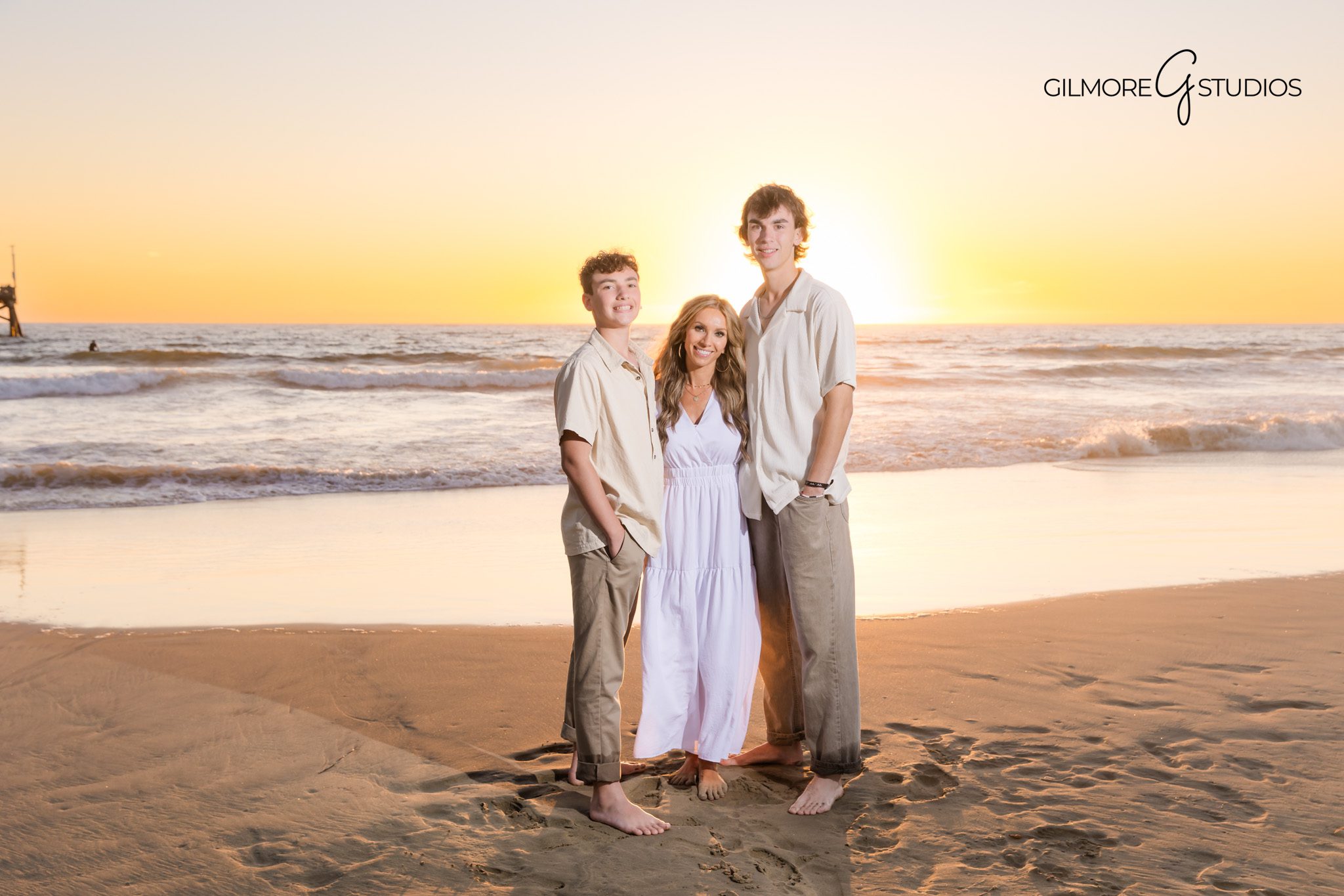 Pier backdrop family portraits with Newport Beach photographer.
Sunset photo session capturing parents with kids near Newport Beach Pier.