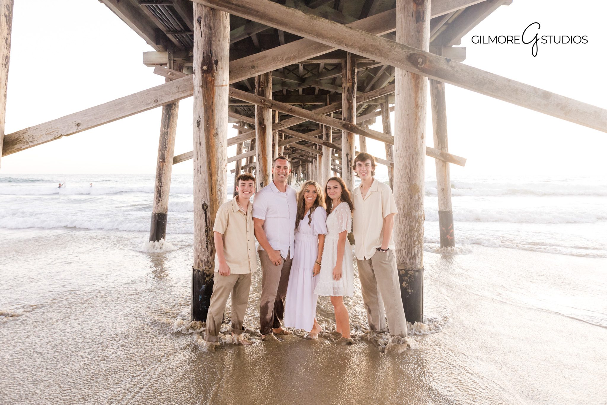 Family photographer capturing warm tones at Newport Beach Pier during sunset.
Newport Beach portrait photography showing family walking along shoreline.