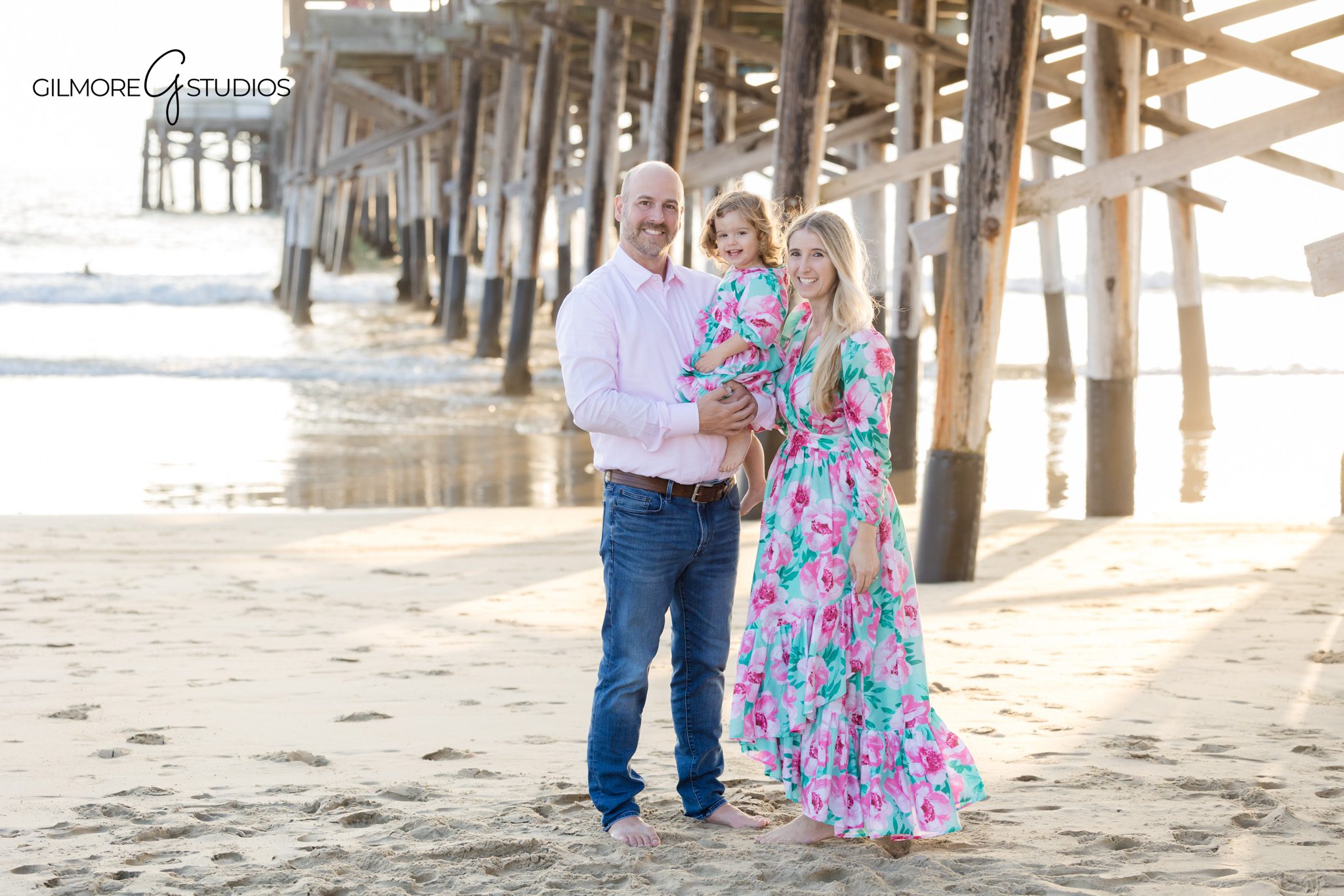 Newport Pier family photographer capturing toddler laughing during beach session.

Newport Beach photography of parents holding their two year old by the ocean.