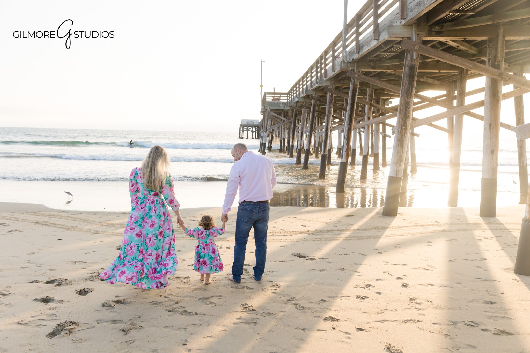 Photographer capturing barefoot family portraits by the shoreline.

Newport Beach portrait of parents lifting toddler in the air.