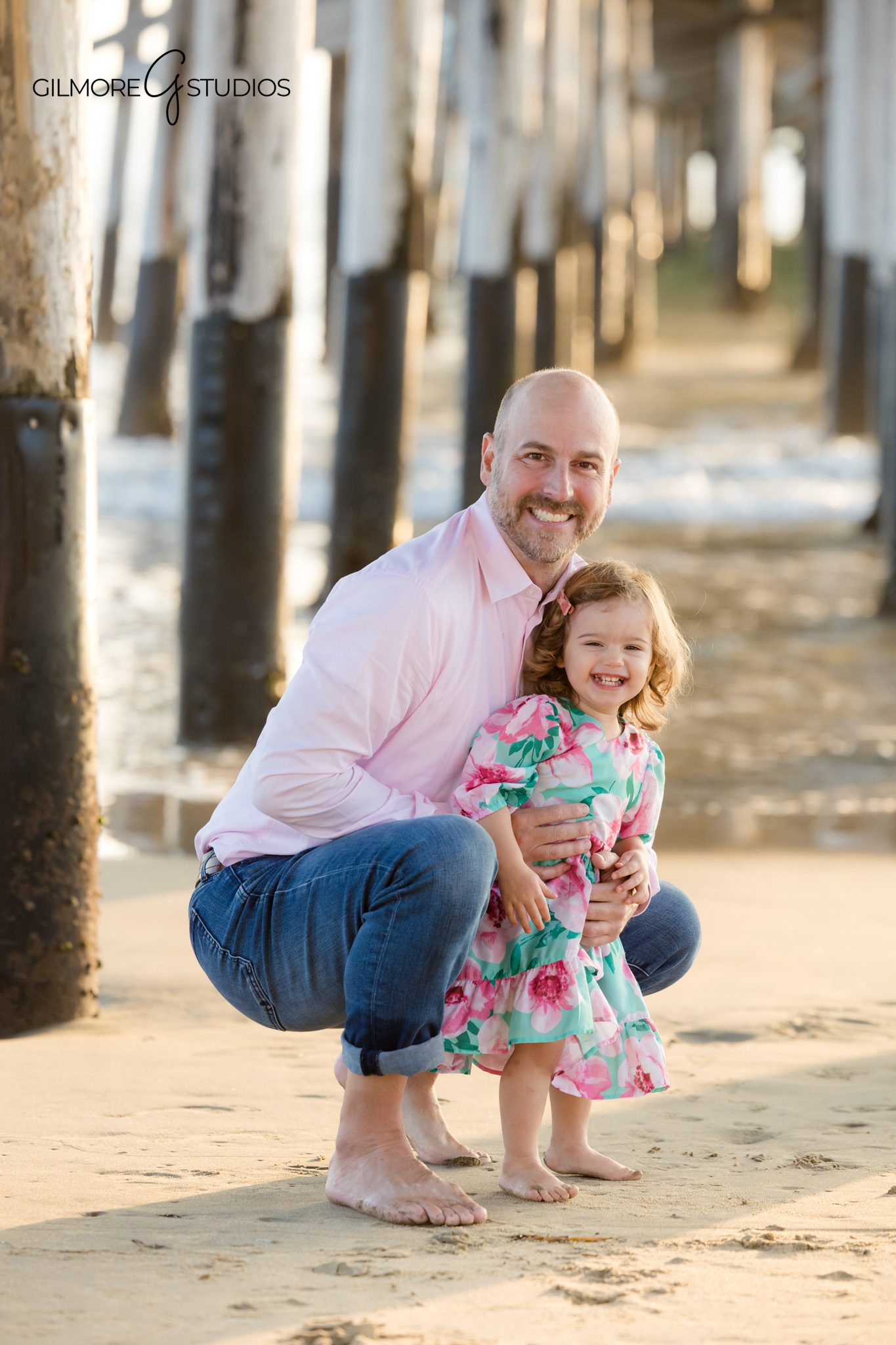 Candid beach photographer capturing toddler running in shallow waves.

Family photography featuring warm golden hour light at Newport Pier.