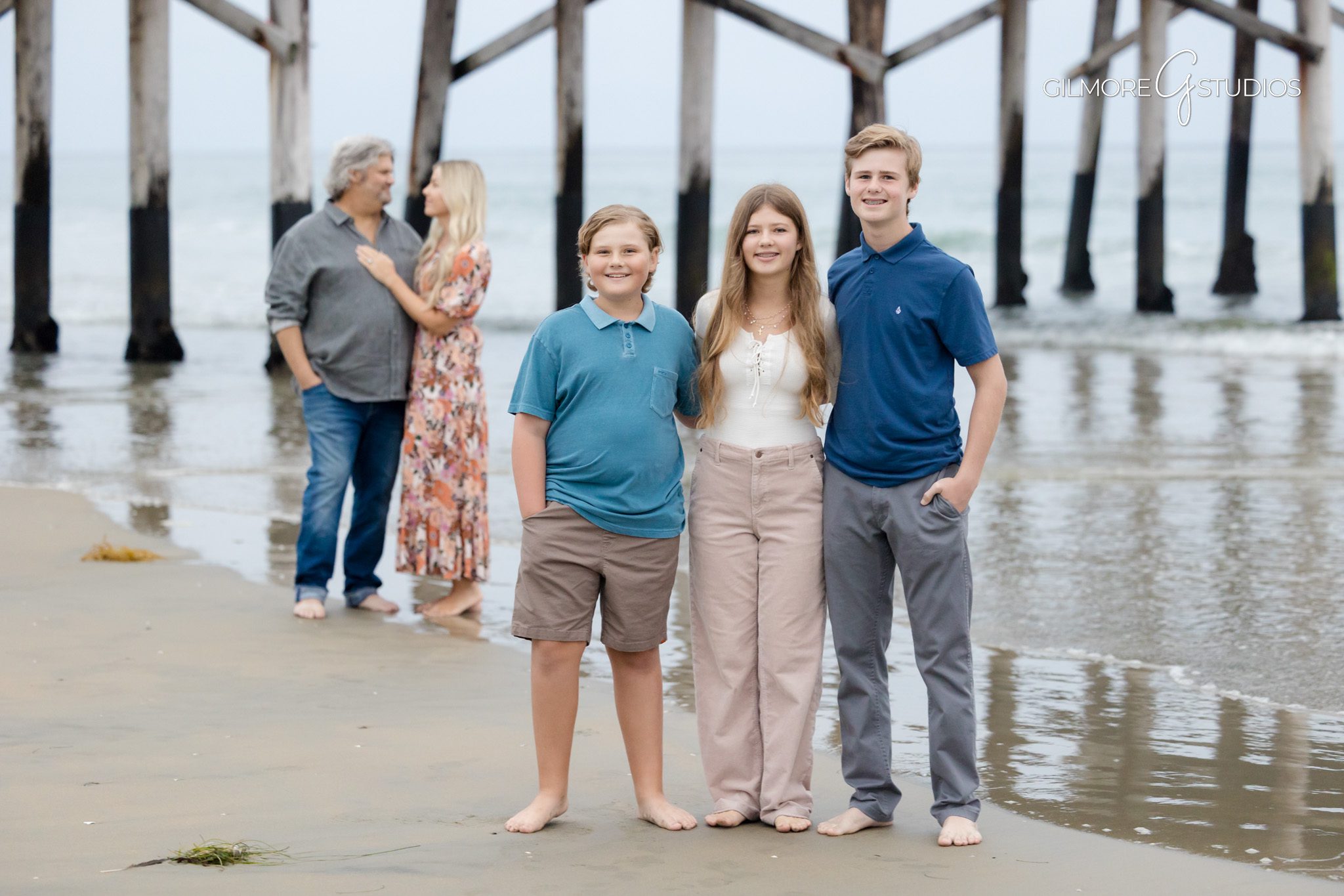Children laughing in Newport Beach family portrait session photography.

Newport Pier portrait photographer photographing family hugging on sand.