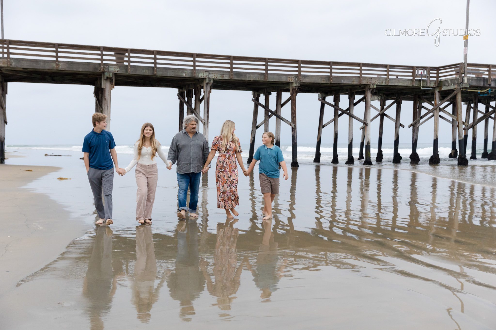 Newport family photography with soft sunset behind pier beams.

Mini session photographer capturing candid walking shot at Newport Beach.