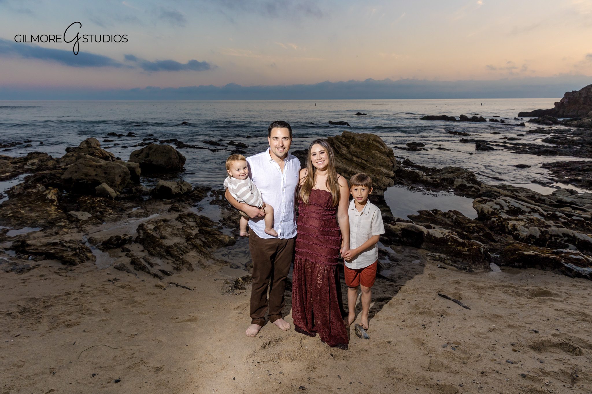 Professional portrait photographer documenting family connection at Little Corona Beach.

Beach family photography session with parents holding children at sunset.