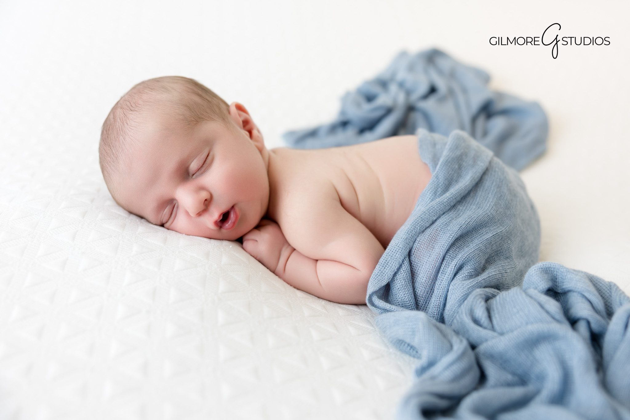Newborn photographer capturing parents holding baby in soft light.

Gilbert newborn photography showing baby wrapped in cream swaddle.