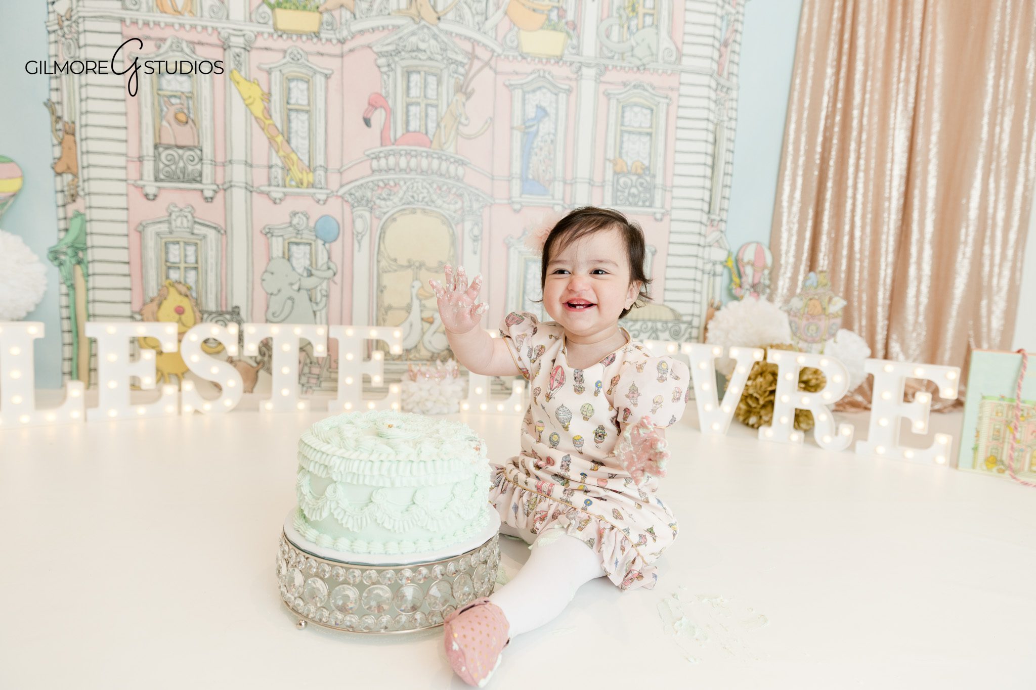 First birthday cake smash session Phoenix studio pastel theme
Baby girl sitting in front of cake smash setup Phoenix photographer