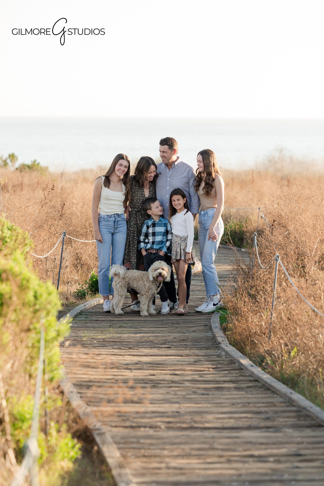 family photographer orange county capturing candid family moment on boardwalk
crystal cove state park family portrait session with tall grass and ocean view