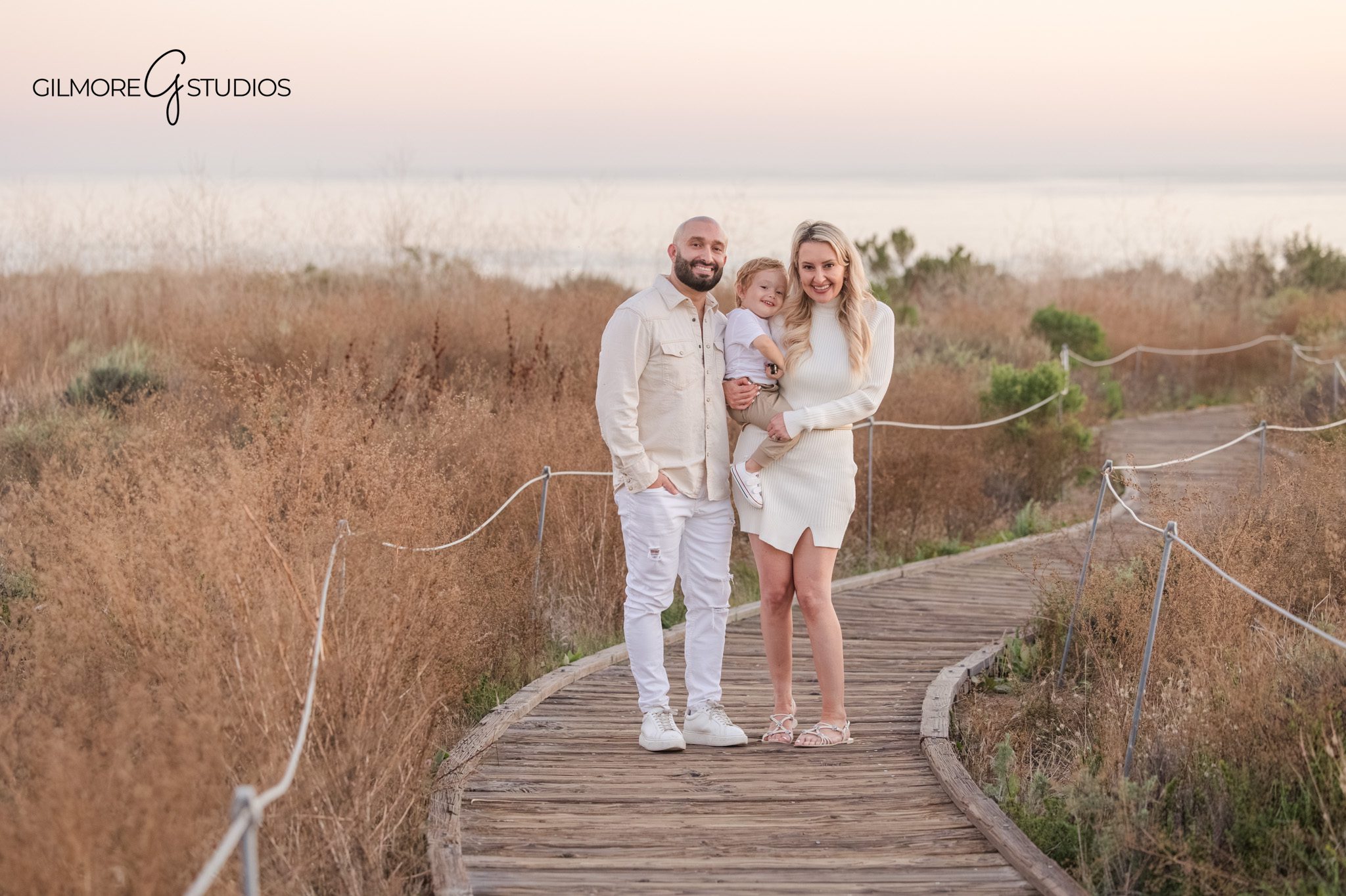 Crystal Cove Newport Beach family photographer sitting on bench portrait photography
Newport Beach family photography parents and toddler on wooden boardwalk portrait