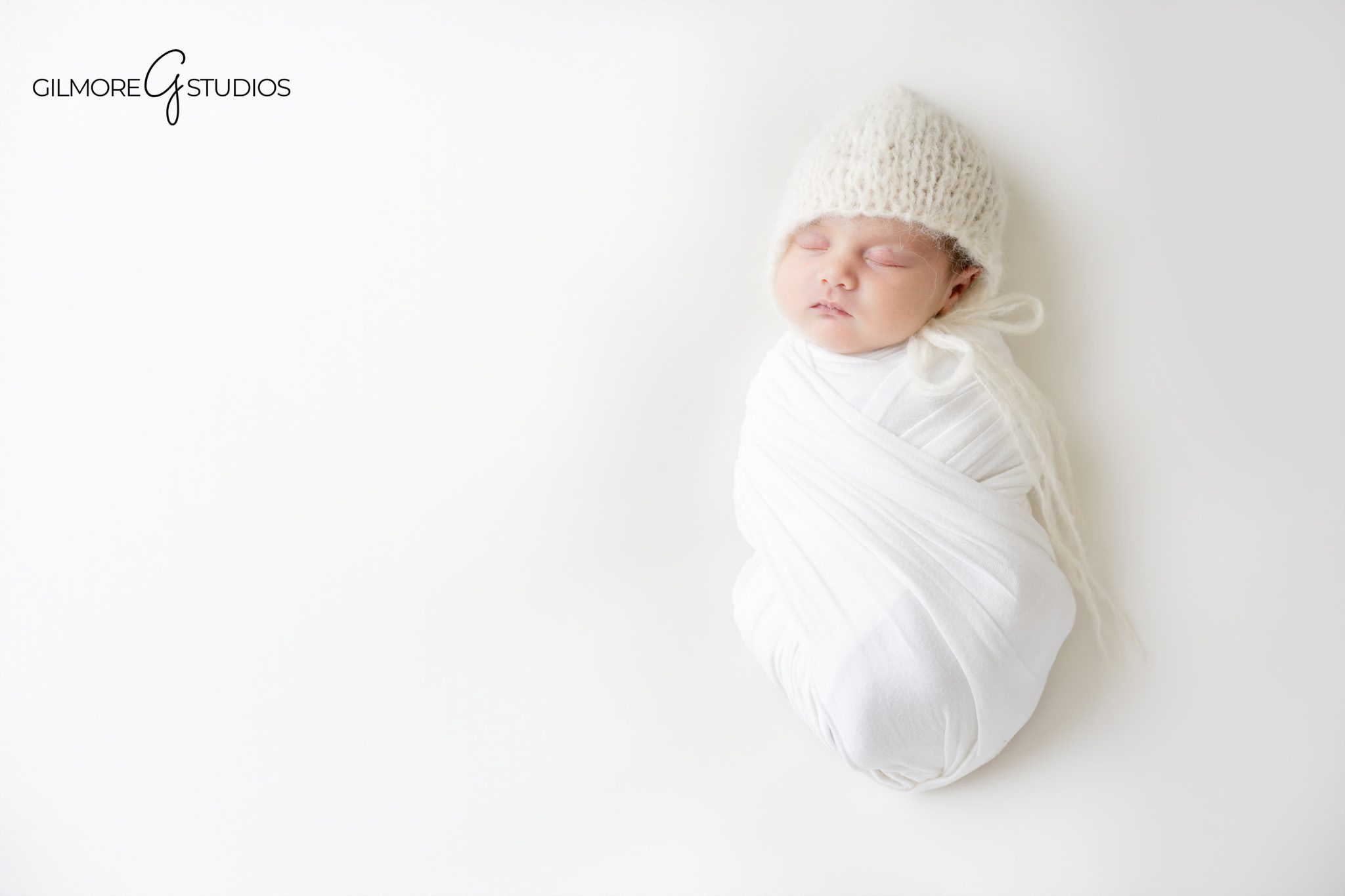Professional newborn portrait photography featuring sleeping infant girl in neutral blush setup