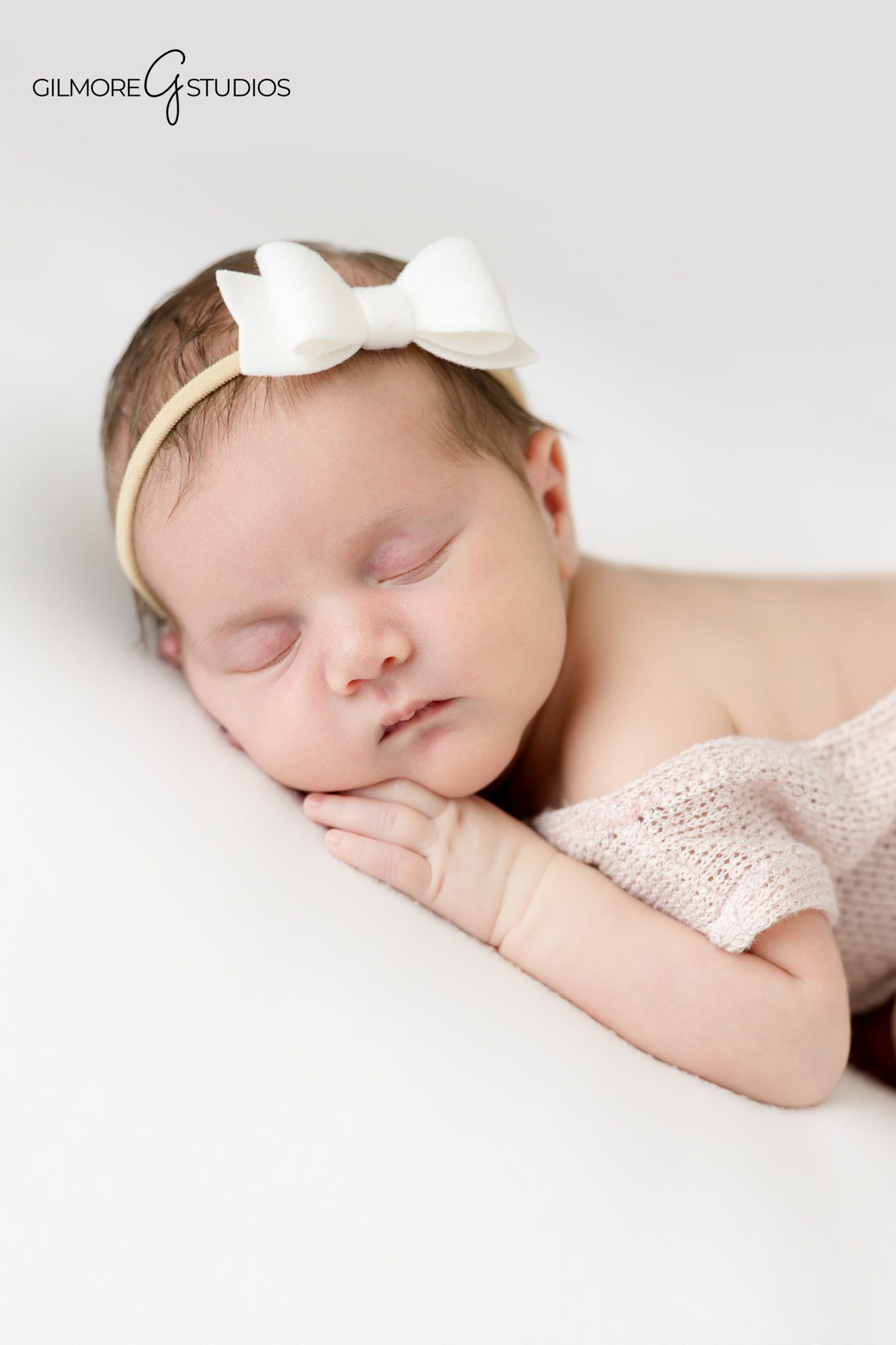 Baby girl posed newborn photography session with blush tones and fluffy cream blanket in Arizona studio