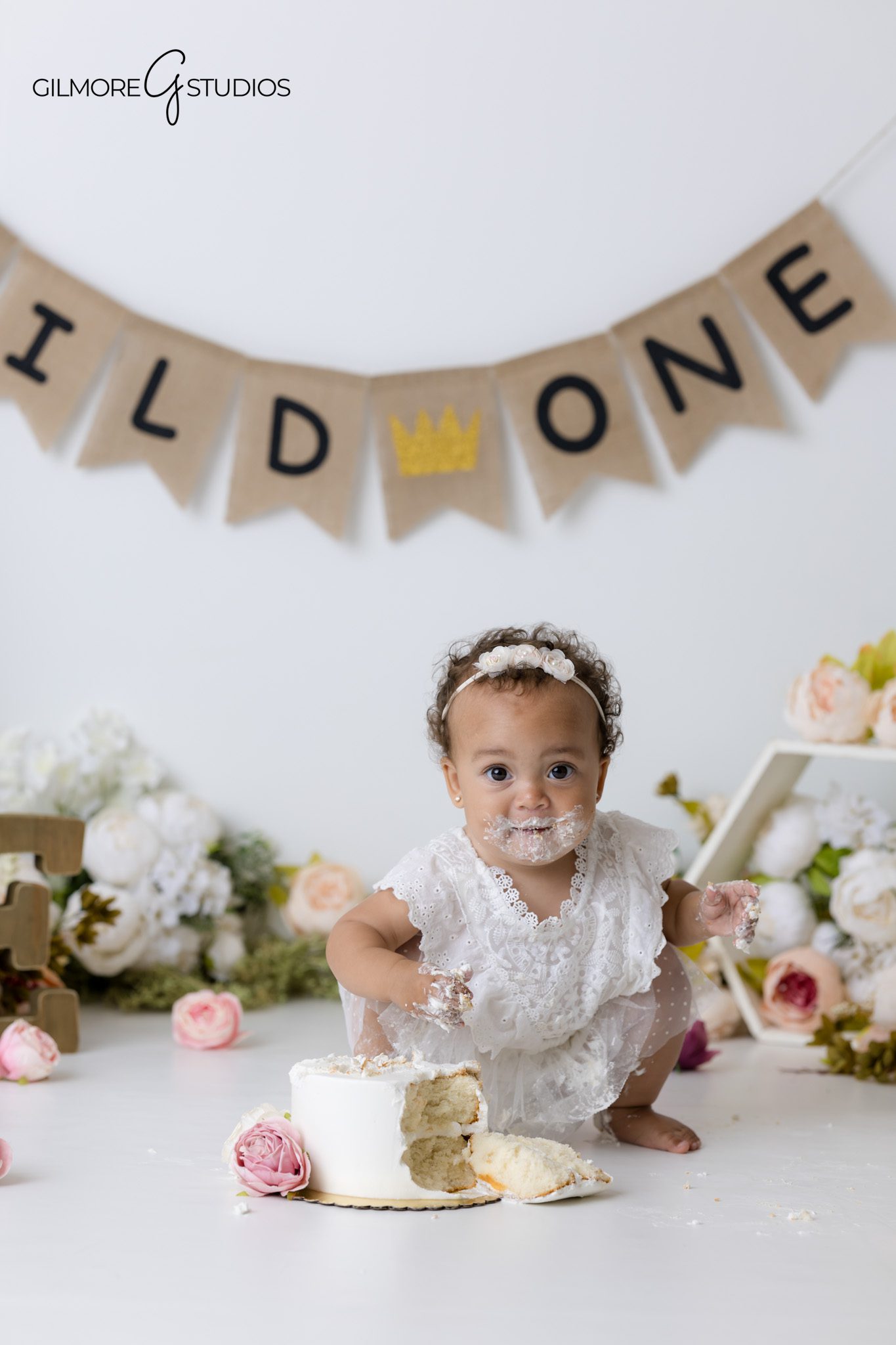 Cake smash photography Gilbert Arizona featuring pink roses, white cake, and one year old baby girl
