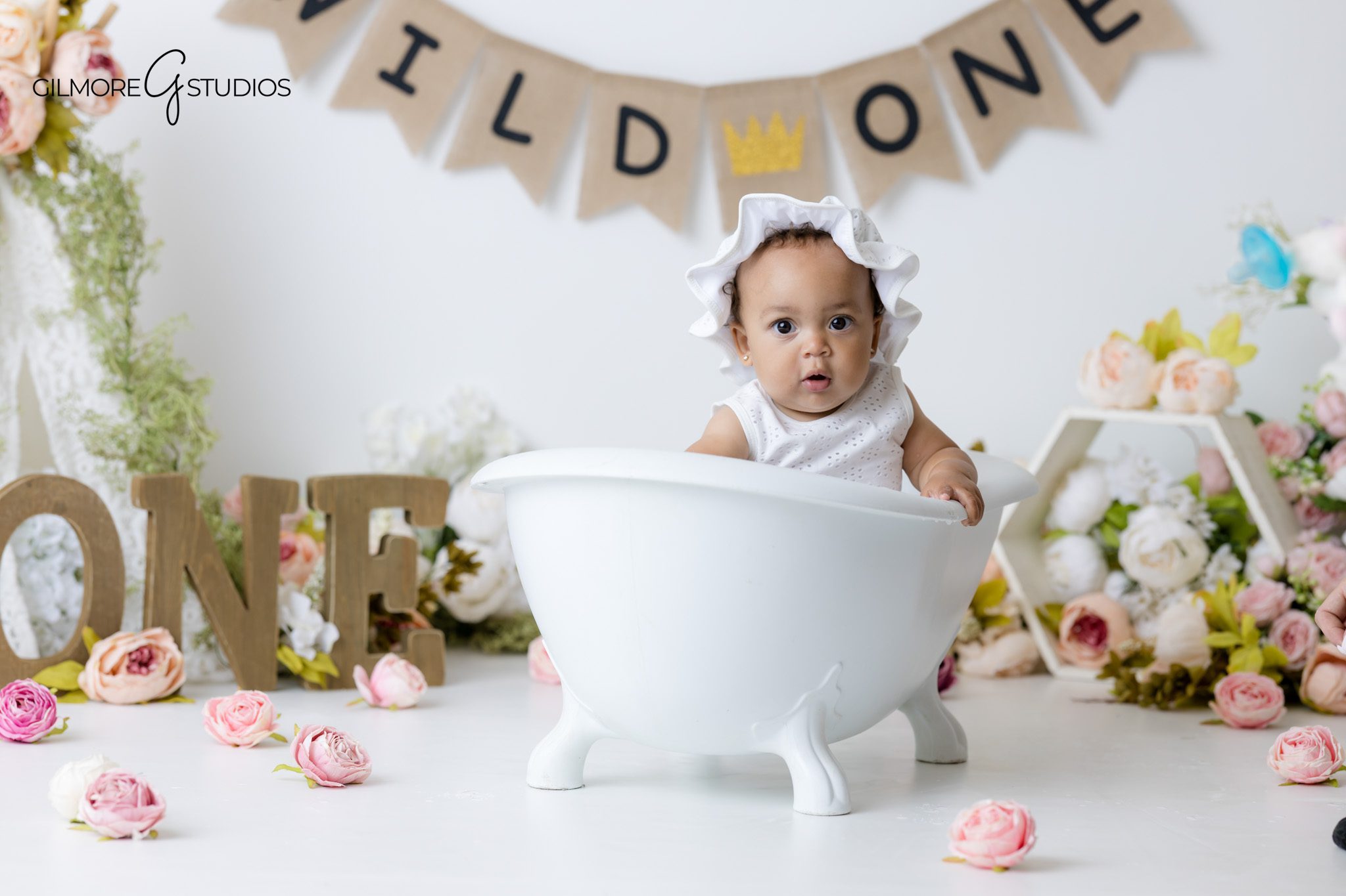 Indoor cake smash photography Gilbert Arizona with soft pink flowers and neutral styling