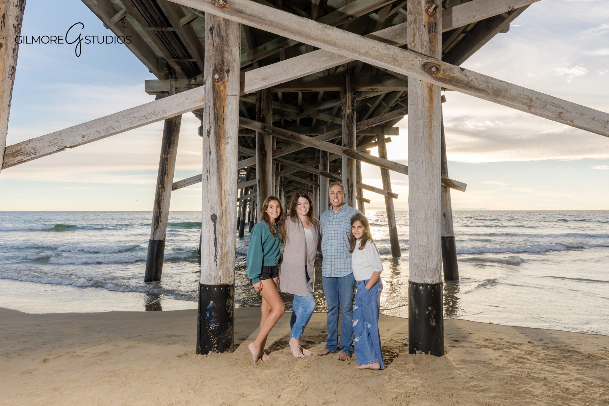 Family hugging near the ocean during a November beach portrait session
Newport Pier family photos with warm fall wardrobe and beach scenery