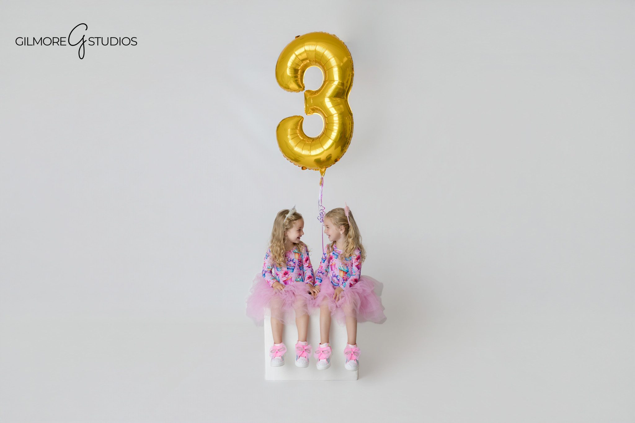 Unicorn cake smash session with twin girls and colorful streamers
Gilmore Studios twin birthday photoshoot with unicorn theme and cakes