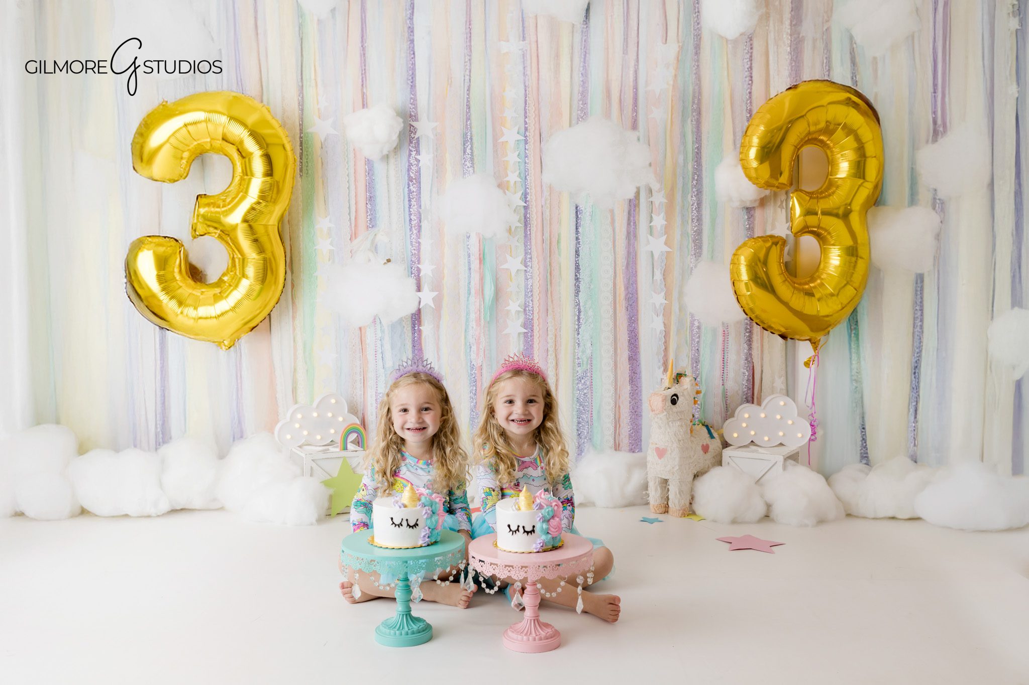 Unicorn theme cake smash for twin girls in a Newport Beach studio
Twin girls sitting side by side with individual birthday cakes