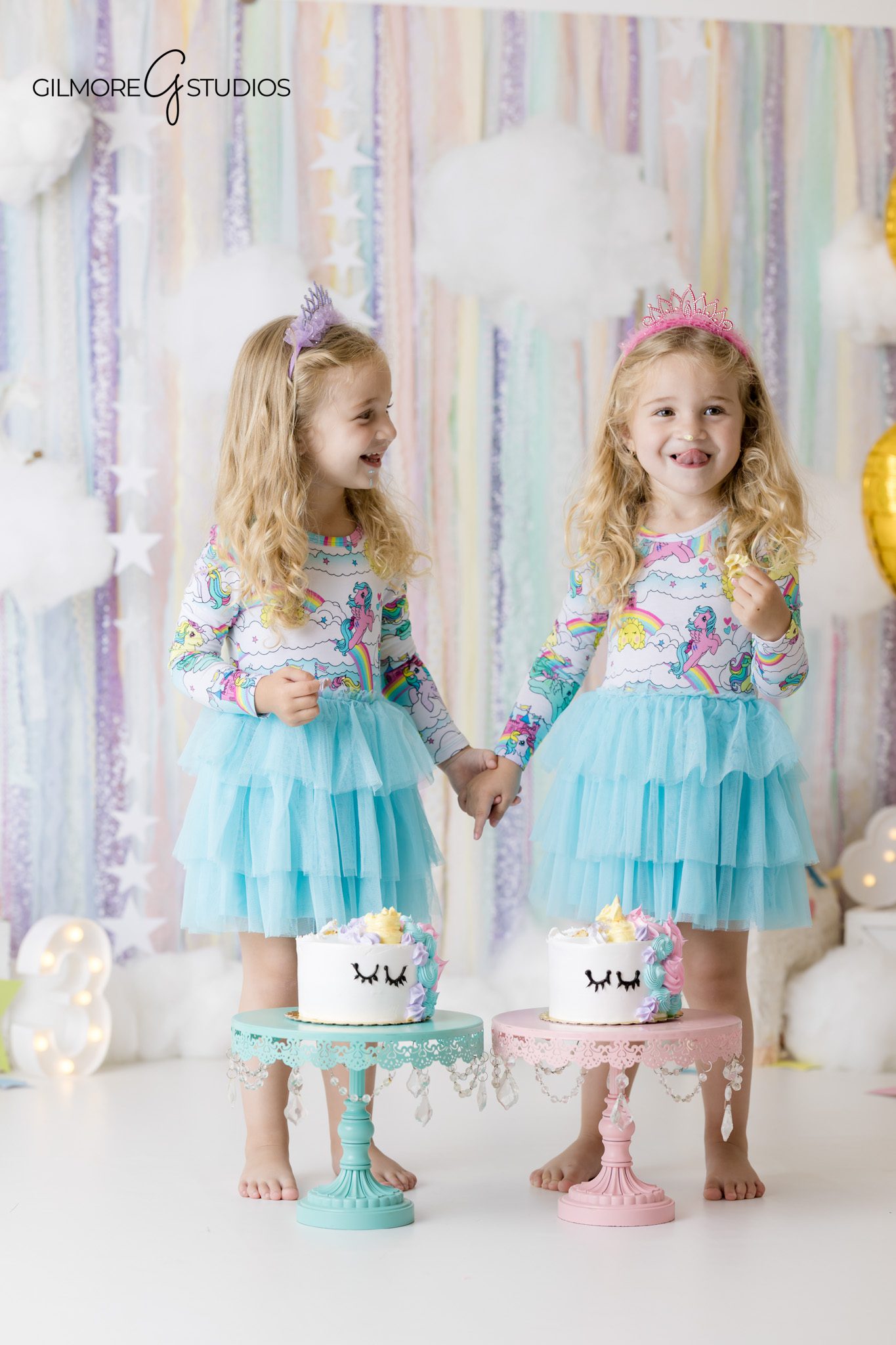 Twin girls holding hands during a unicorn birthday photoshoot
Unicorn birthday cake smash with twin sisters at Gilmore Studios