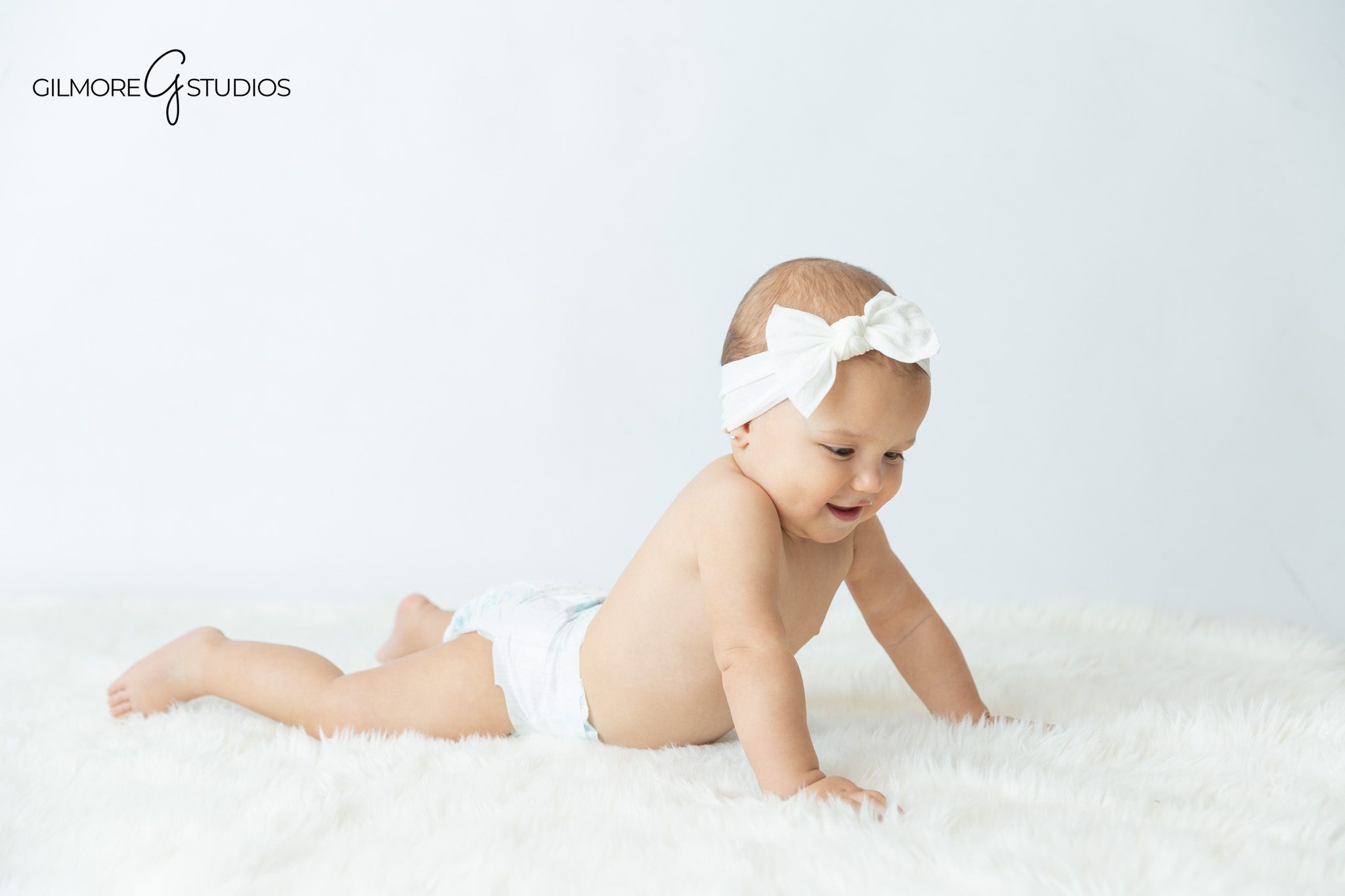 Baby sitting up milestone photos with neutral wardrobe and soft studio light
Sitting up milestone session with baby laughing at parents
