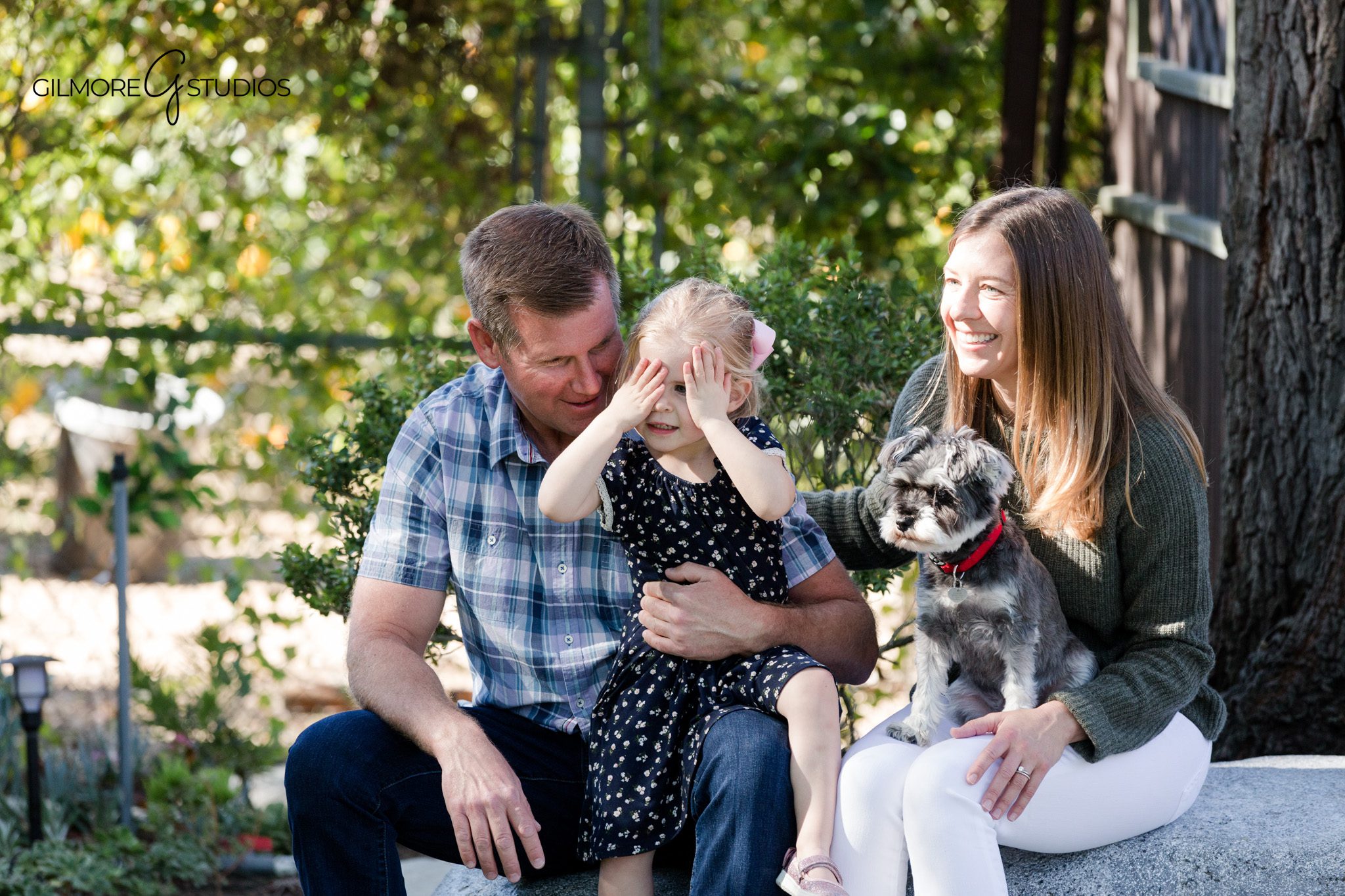 Family of four photographed in their backyard garden at golden hour
Backyard garden portrait session with soft greenery and family connection
