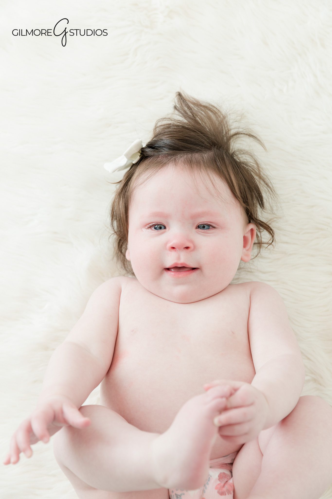 Baby sitting up session with soft blanket and neutral backdrop
Seven month baby photos during sitting up milestone session