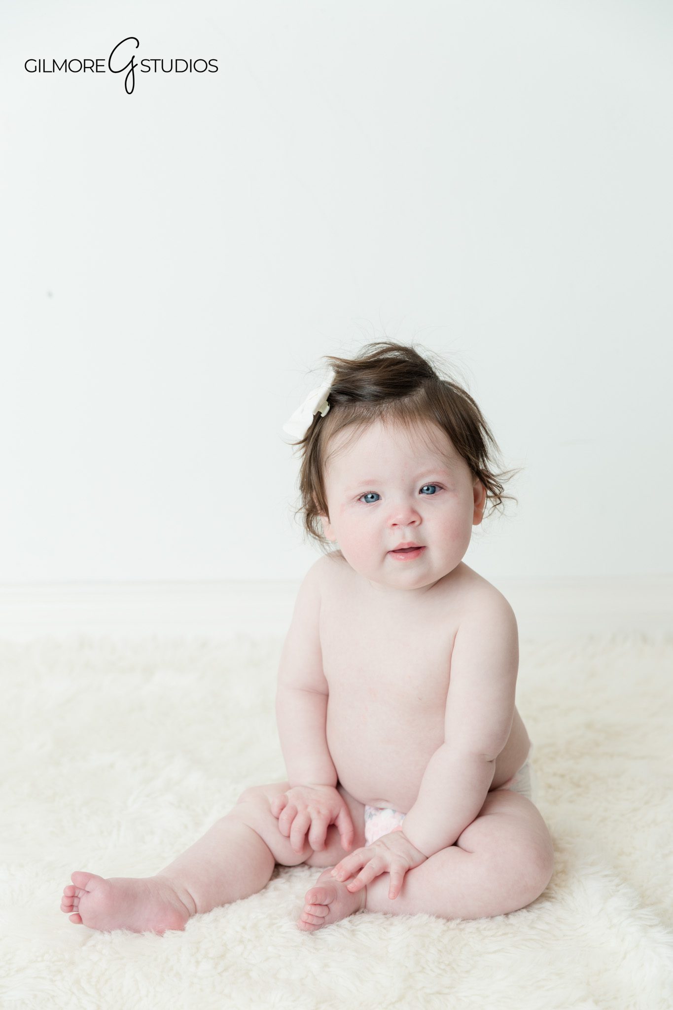 Baby sitter session with simple outfit and neutral studio setup
Six month old baby laughing during sitting up milestone photos