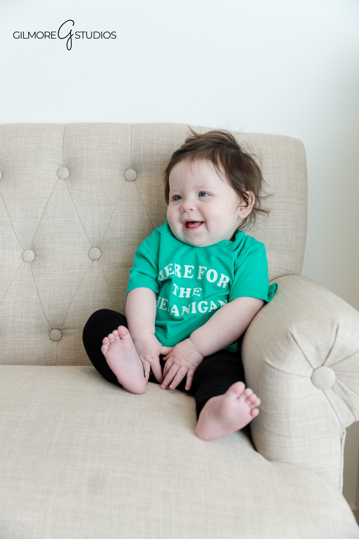 Baby milestone portraits with baby sitting safely on soft surface
Baby sitting independently with curious expression during studio photos