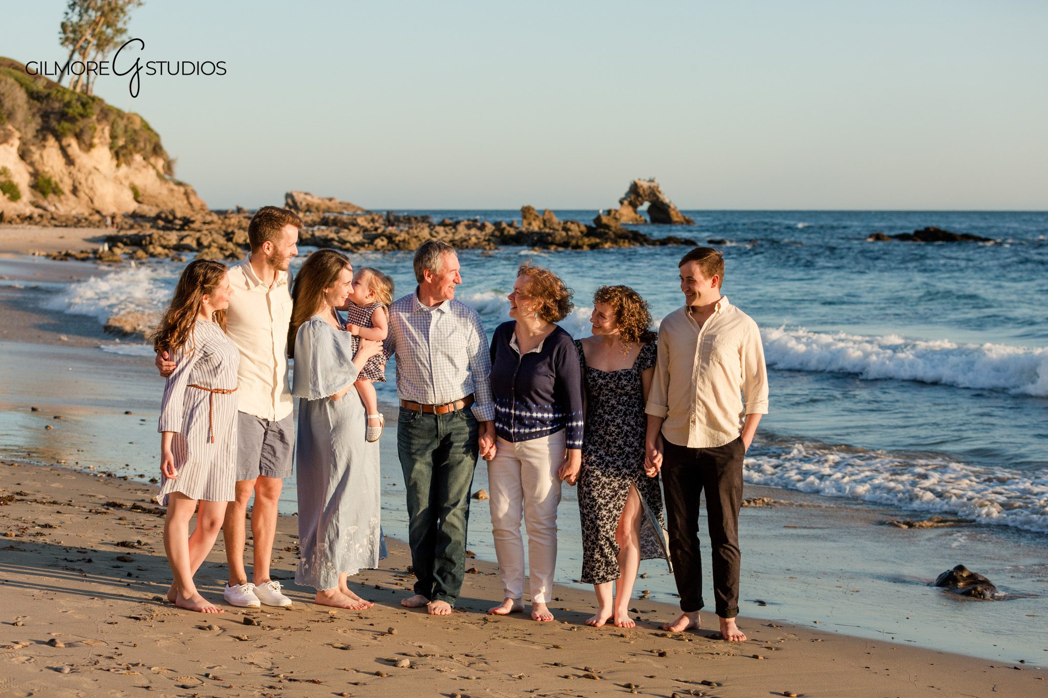 Rocky coastline portraits with grandparents seated and family gathered around
Newport Beach beach session with coordinated neutral and blue outfits