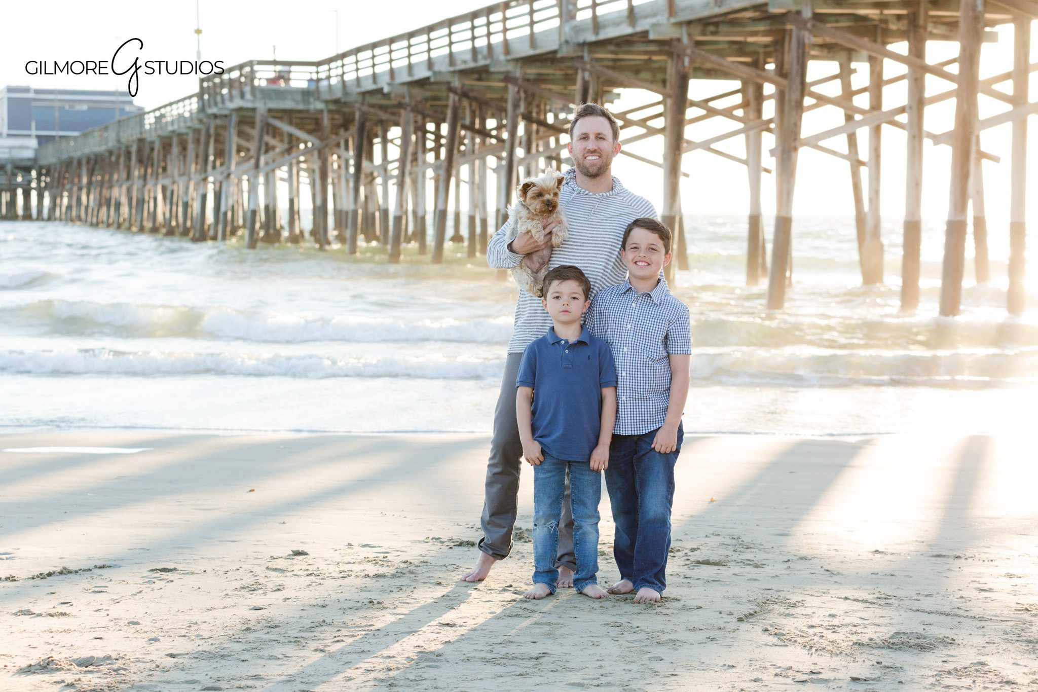 Family of four photographed at Newport Pier during golden hour
Newport Beach family portraits with children running barefoot in the sand