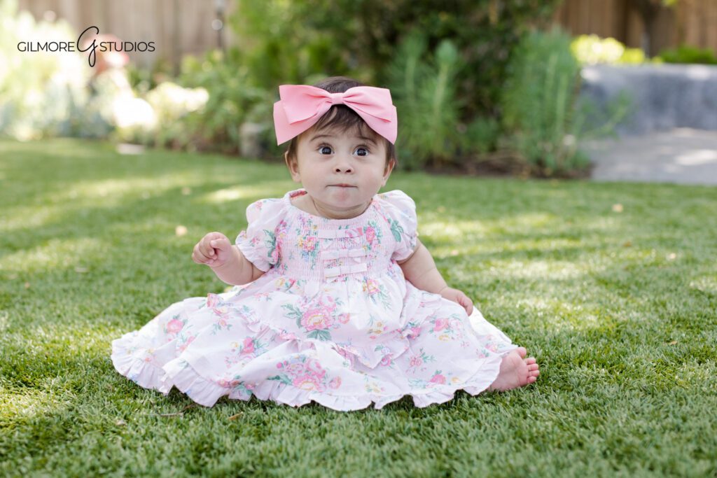 Gilbert AZ baby milestone photographer for 6 to 9 month portraits
Baby girl sitting on white studio floor with floral details