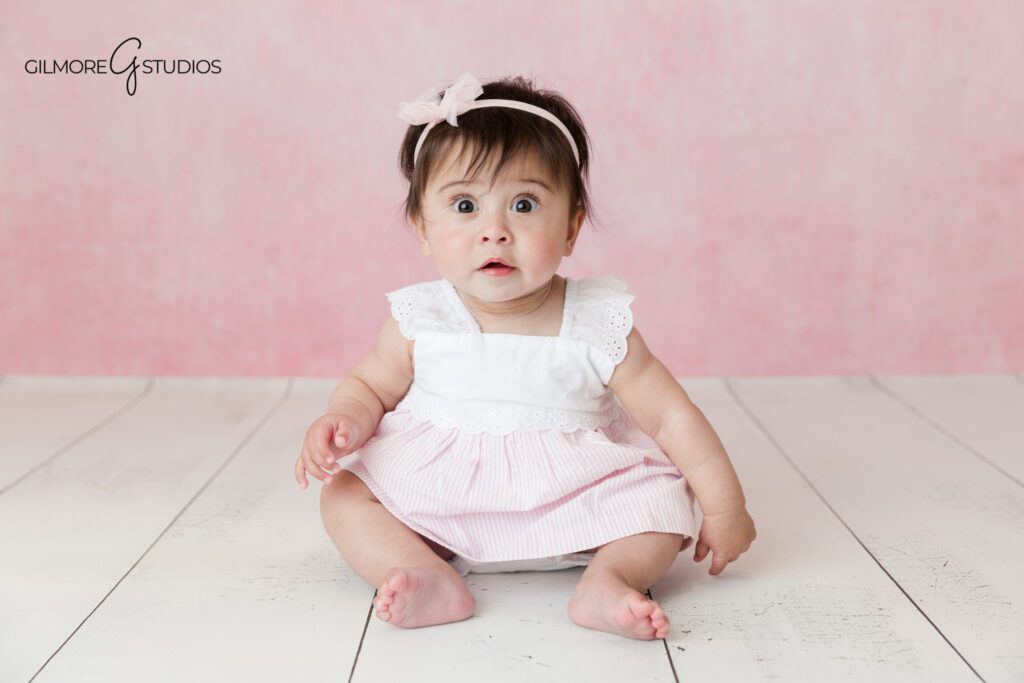 Sitting up baby photos with light neutral studio backdrop
Baby girl milestone portrait with soft flowers and white crates