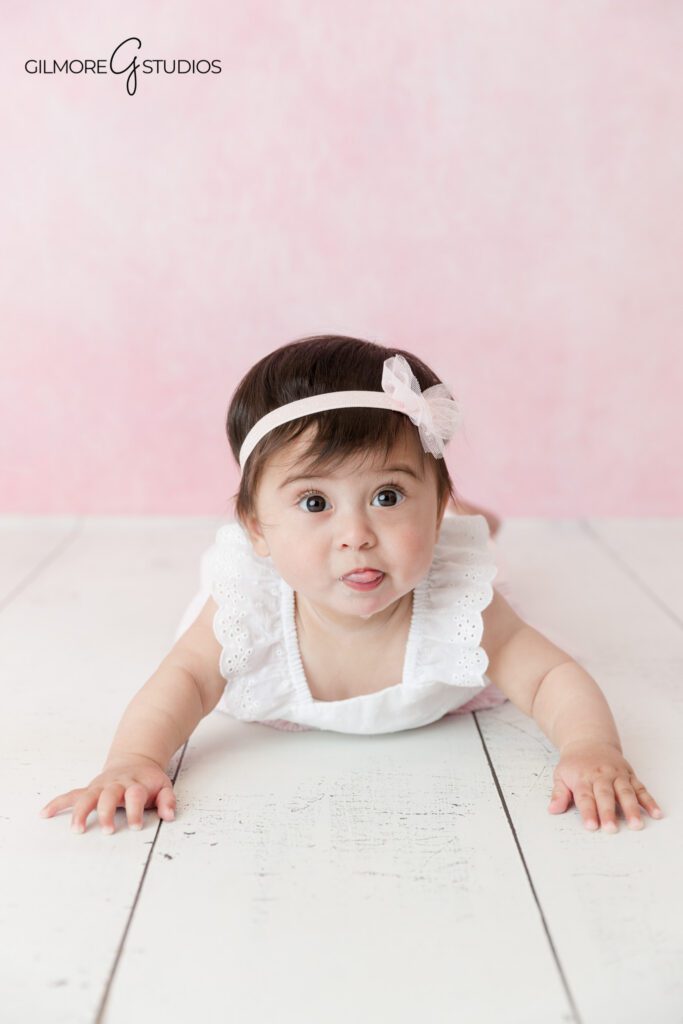 Baby girl milestone session with floral romper and soft studio styling
Sitting up baby girl photos with white backdrop and peach flowers