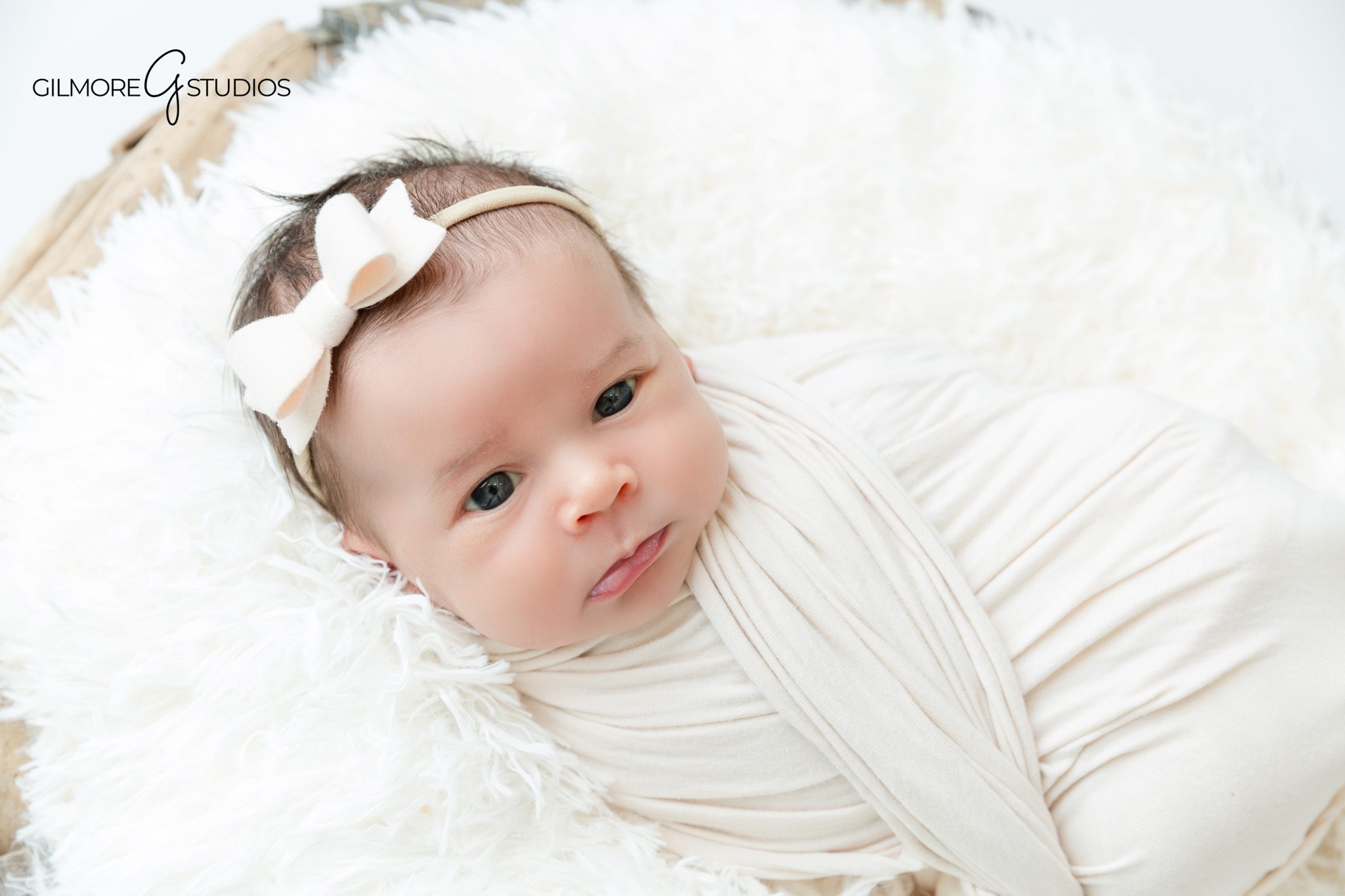 Soft white newborn portrait with baby girl and lace headband
Baby girl posed safely on white blanket for newborn photos