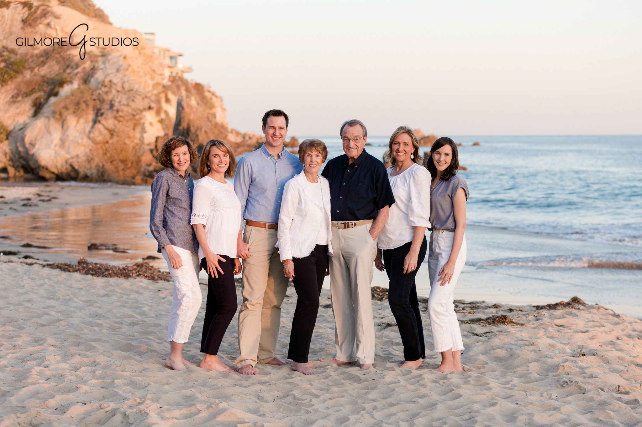 Corona del Mar family photos with rock formations and ocean views
Grandparents holding hands with grandchildren during beach family photos