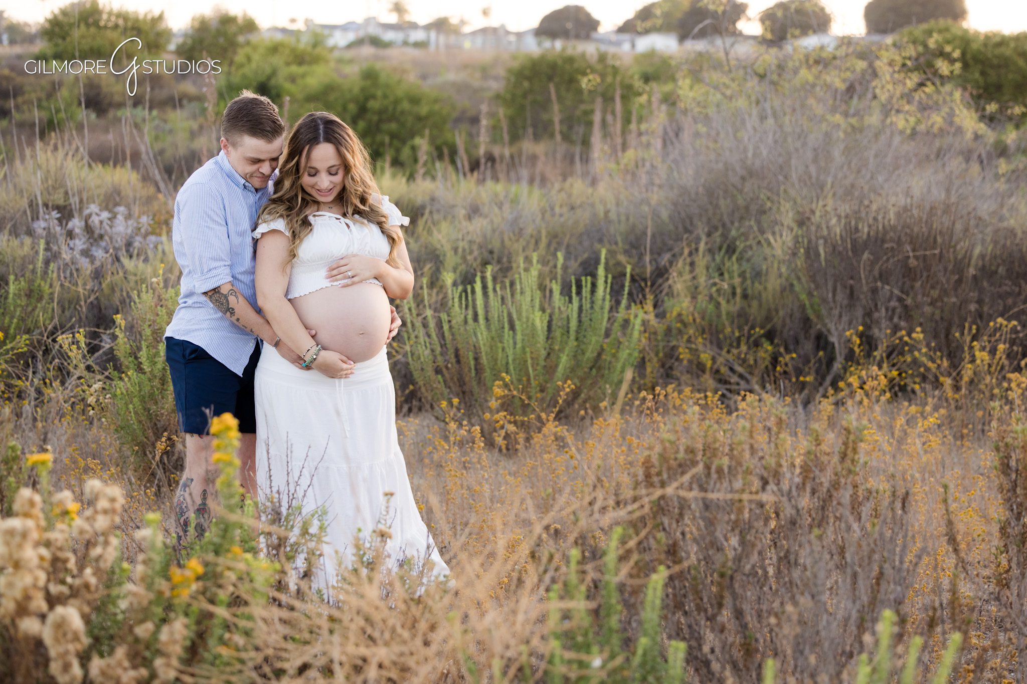 Couple holding baby sweater during maternity session before surprise proposal
Engagement ring on hand resting on baby bump during maternity photos