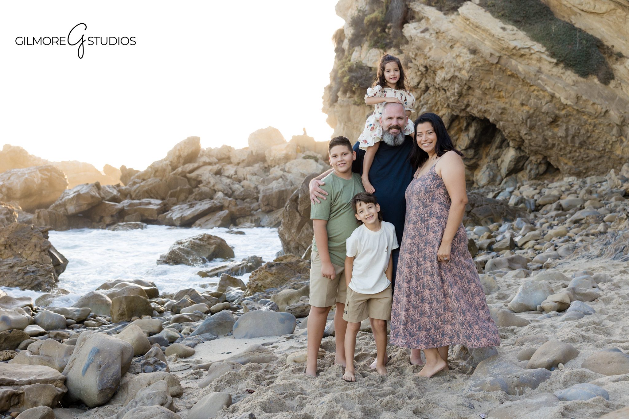 Corona del Mar family photos with soft neutral wardrobe and coastal scenery
Little Corona Beach portraits with siblings laughing together near the water