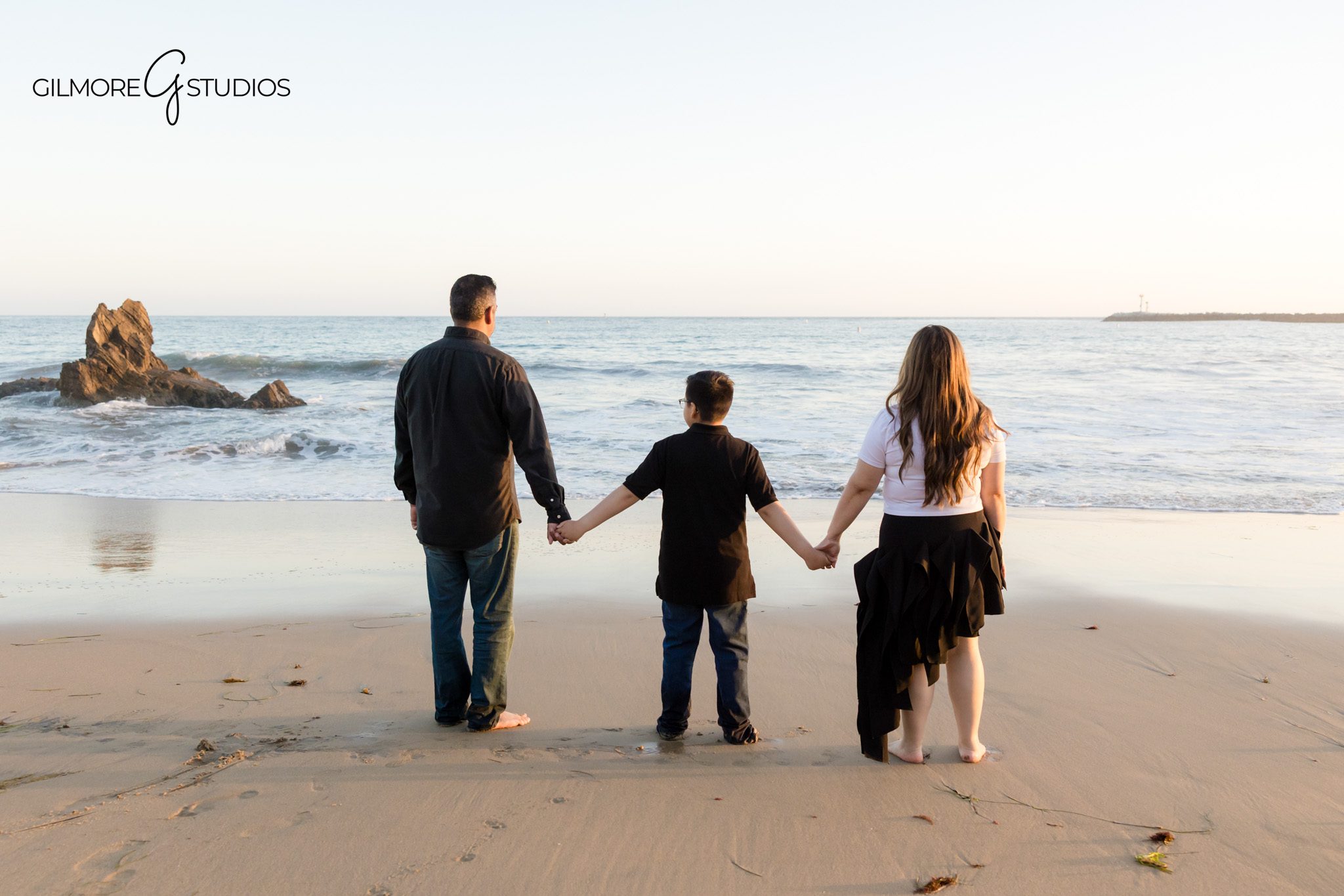 Big Corona Beach golden hour session with natural family connection
Child walking between parents during Newport Beach family photos