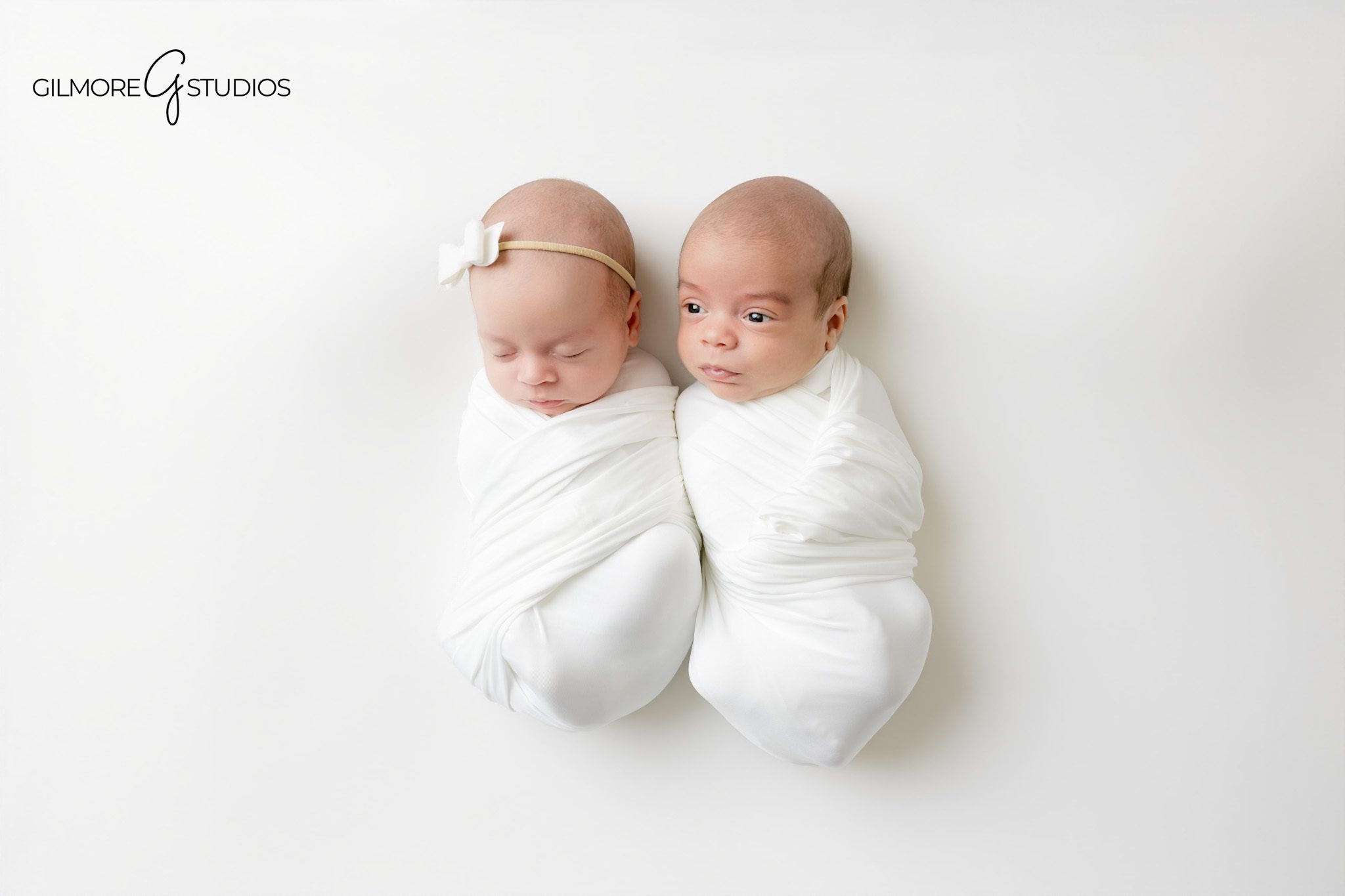 Newborn twins wrapped in white for timeless studio portraits
Twin newborn session with baby boy and baby girl wrapped together