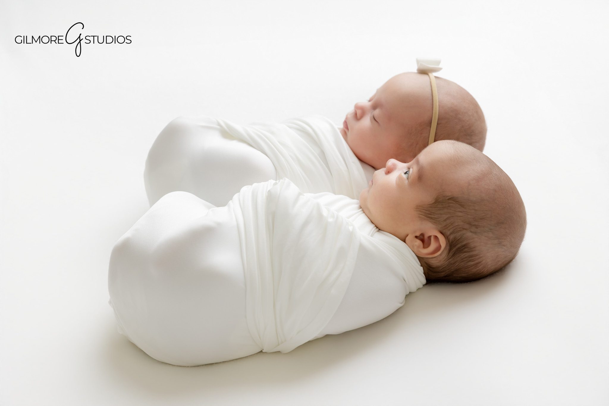 Newborn twins sleeping together in soft pastel wraps
Twin newborn portraits with gray and pink bonnets
