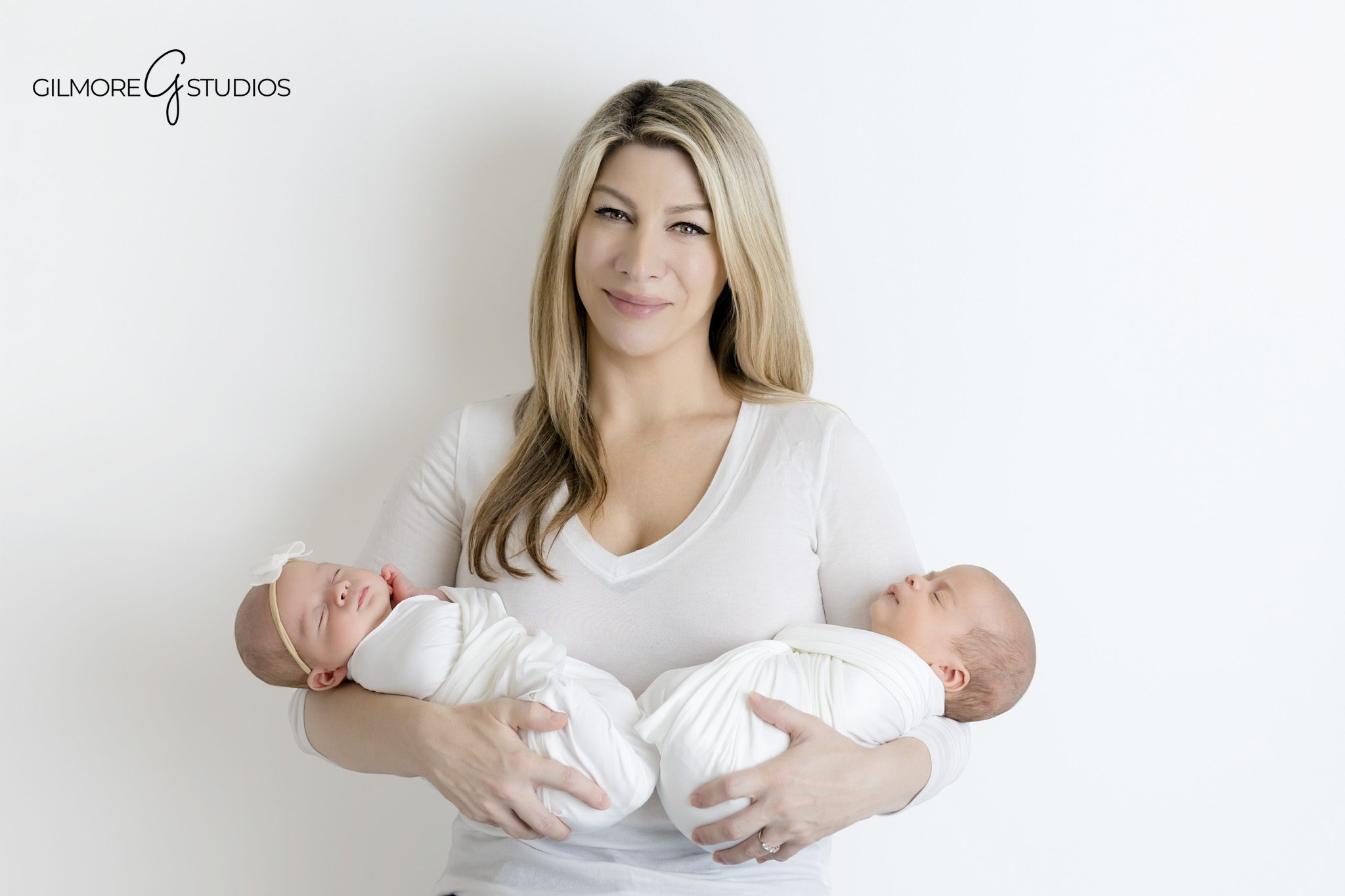Newborn twins photographed with sisters in matching floral dresses
Sibling portraits with newborn twins on white studio backdrop