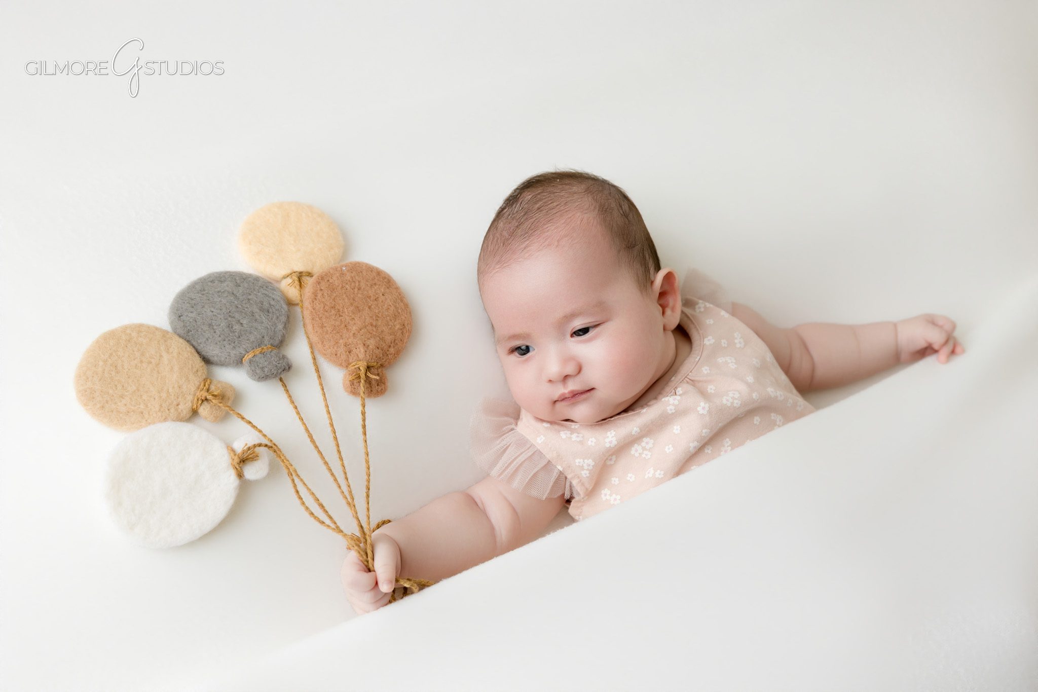 Two month old baby girl in basket during studio newborn photos
Baby girl smiling in basket for older newborn portrait session