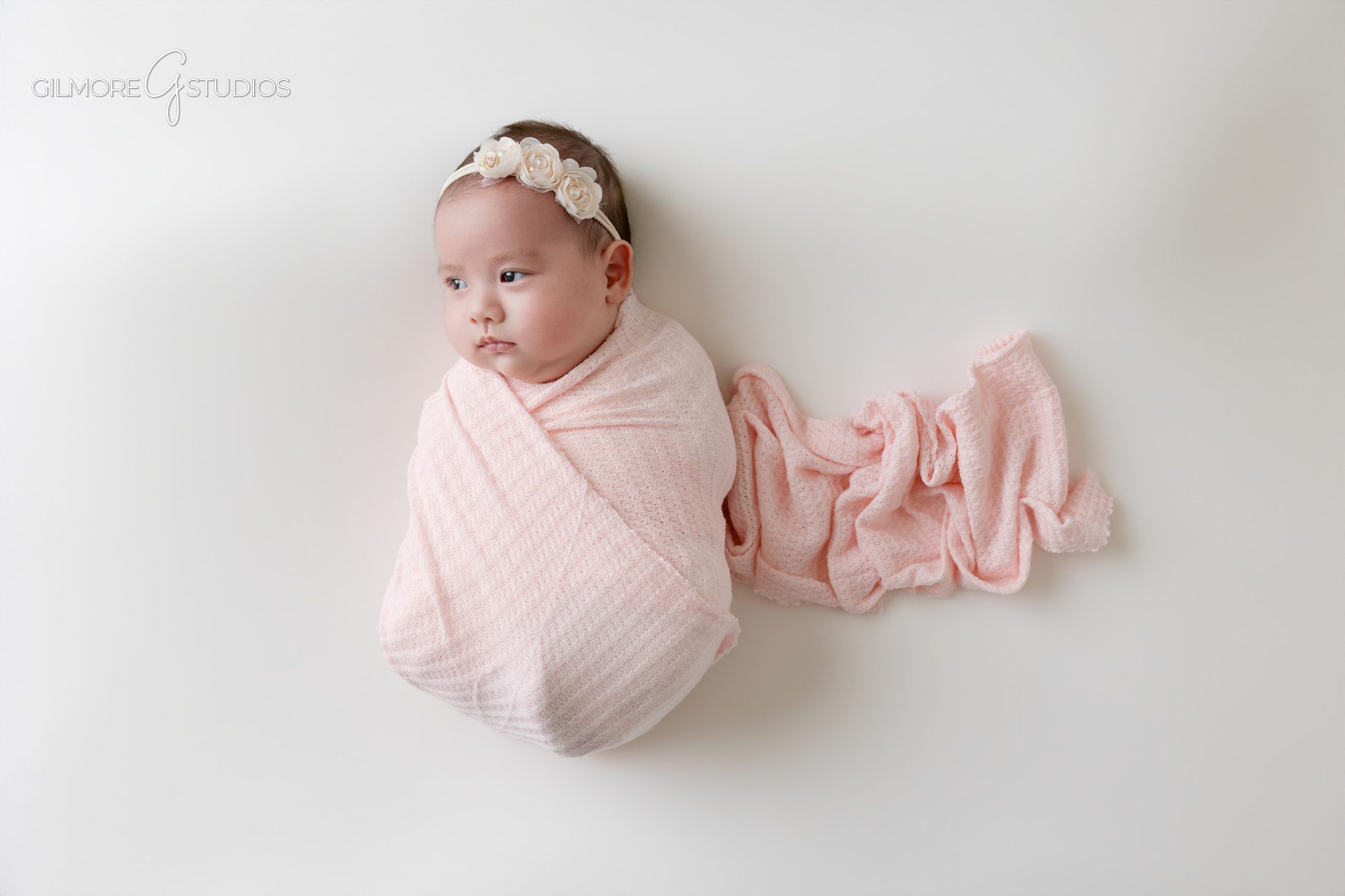 Baby girl in pink romper during older newborn studio photos
Two month old baby portrait on clean white studio backdrop