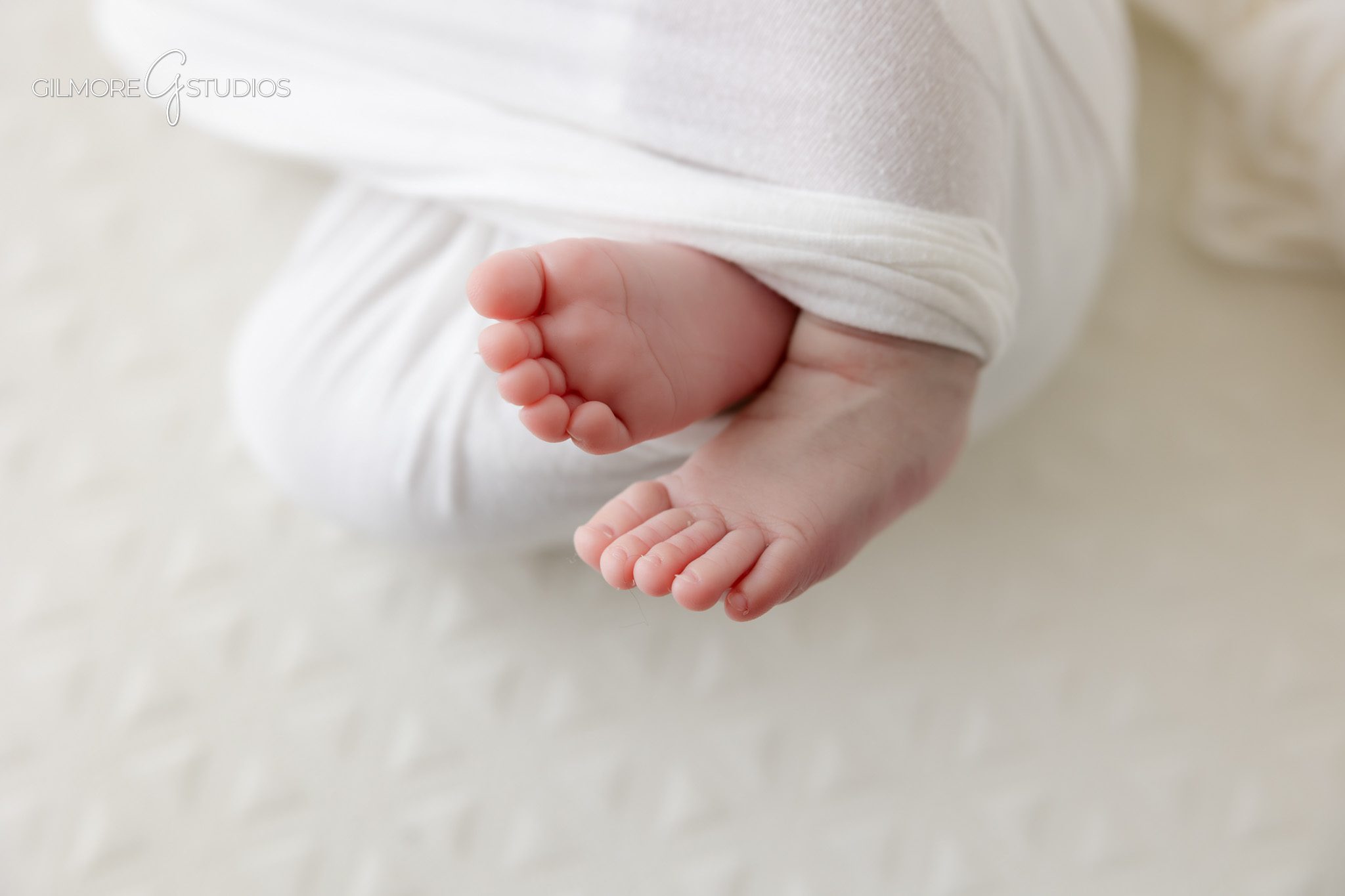 Baby girl wearing white bow during older newborn basket photos
Older newborn portrait with white wrap and cream basket blanket