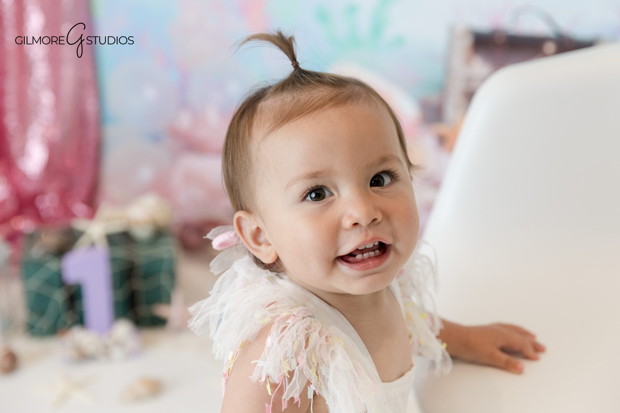 Baby girl sitting on white chair for mermaid themed birthday photos
Under the sea first birthday session with pink and aqua decor