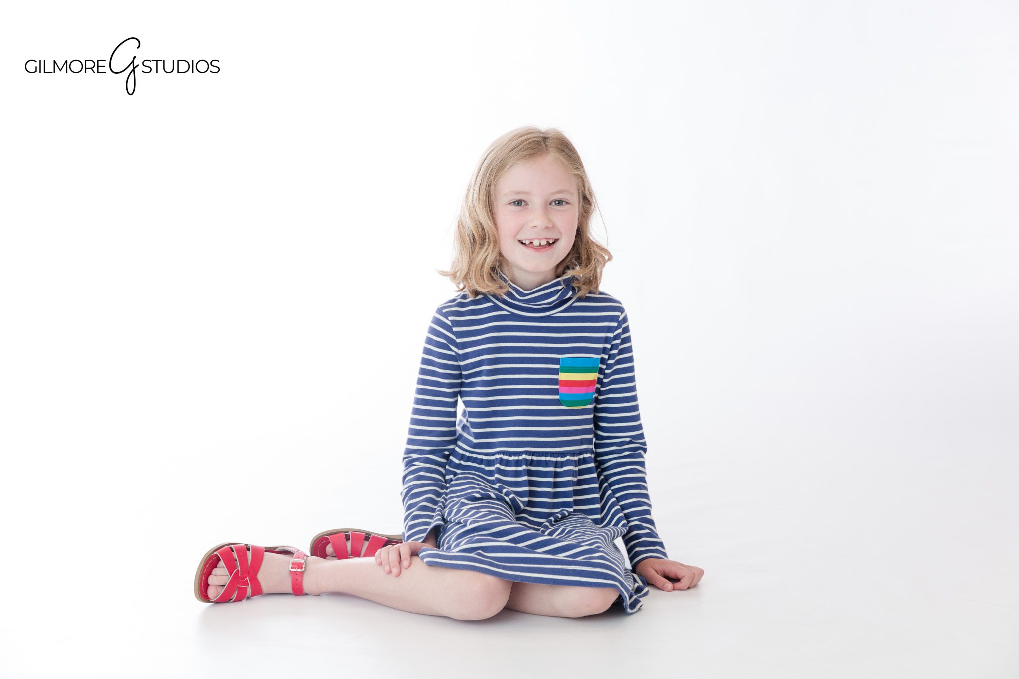 Studio portrait of sisters standing together in striped dresses
Newport Beach children’s photography with coordinated sibling clothing