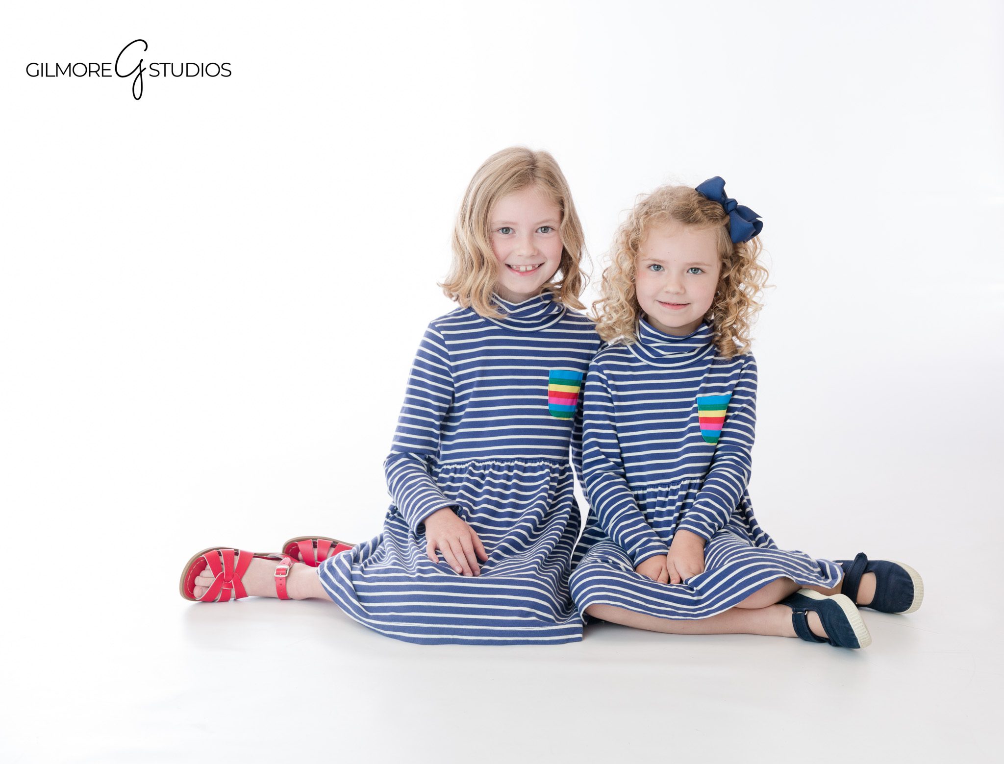 Newport Beach children’s photographer capturing sisters in matching striped dresses
White studio sibling session with two sisters in blue striped outfits