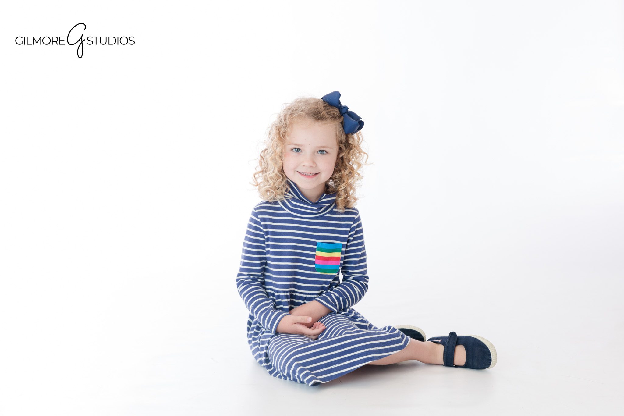 Sweet sibling pose with sisters facing each other in studio
White studio portrait of sisters holding hands