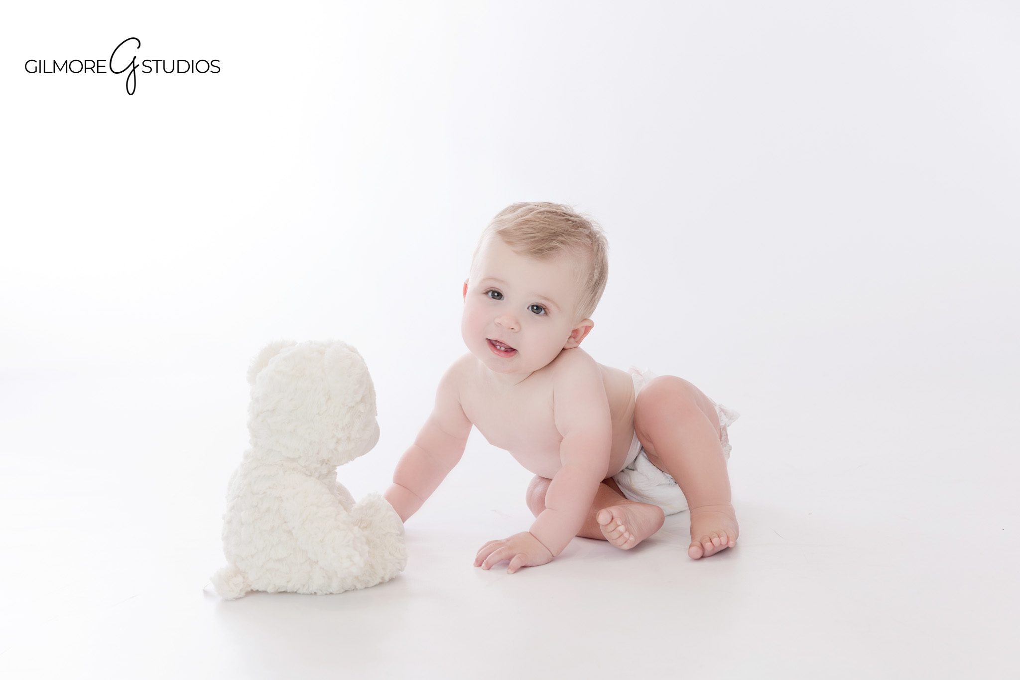 Teddy bear cake smash with one year old boy in light blue romper
Baby boy smiling beside teddy bear cake and birthday set