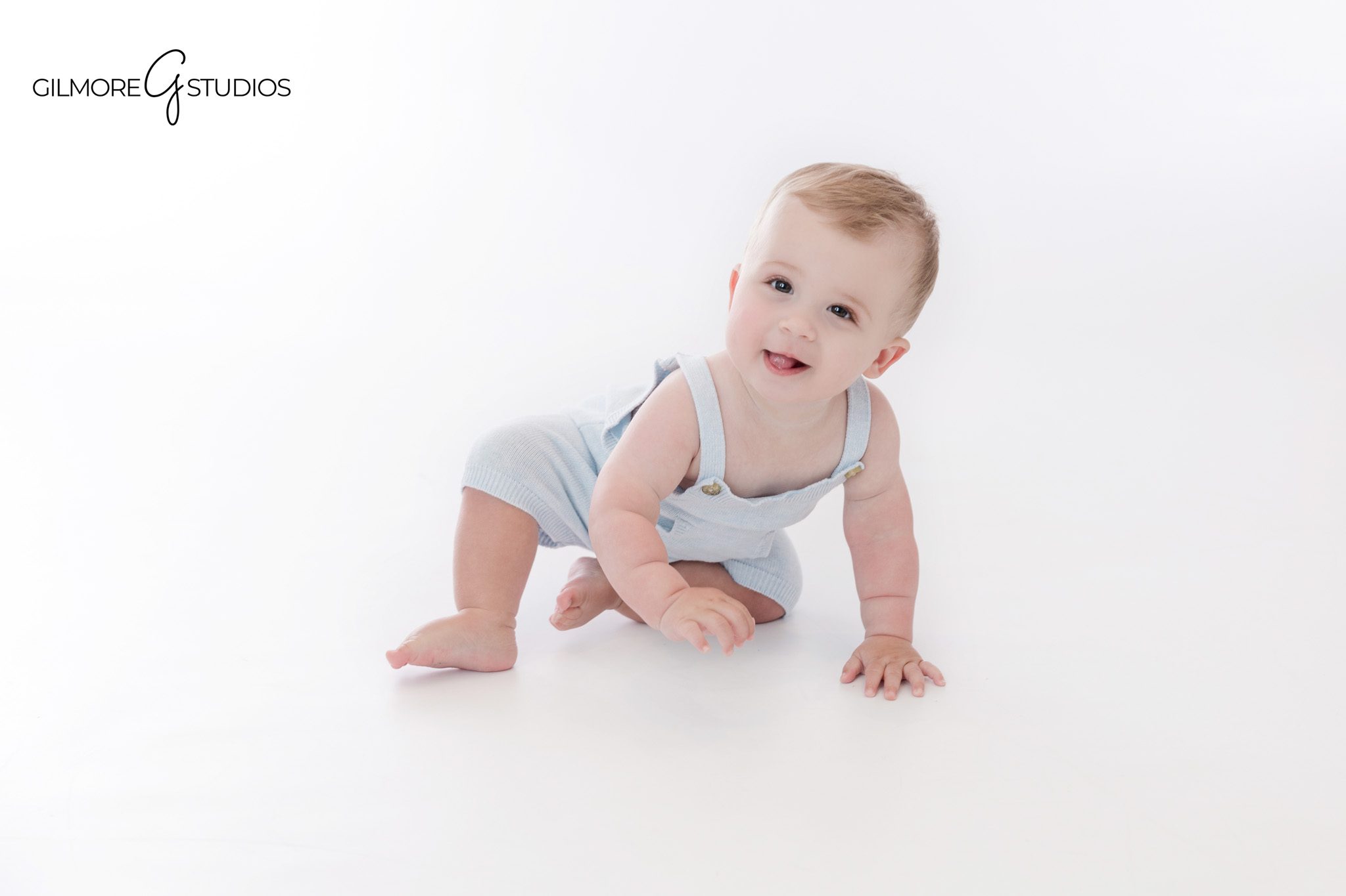 One year old boy smiling in front of teddy bear first birthday cake
Studio cake smash session with teddy bear cake and ONE sign