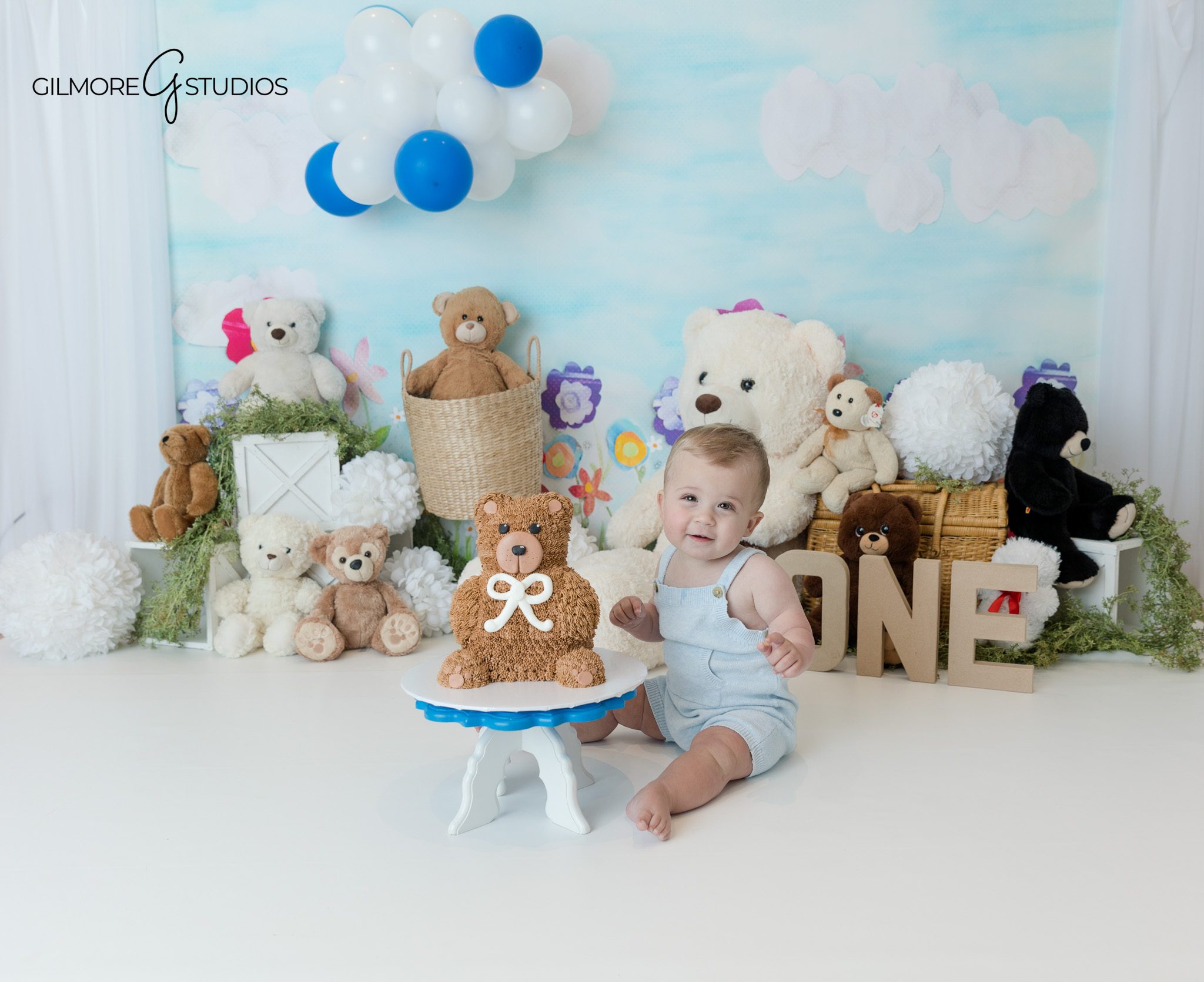 Baby boy sitting with teddy bears during first birthday studio session
Queen Creek first birthday photos with soft white studio background